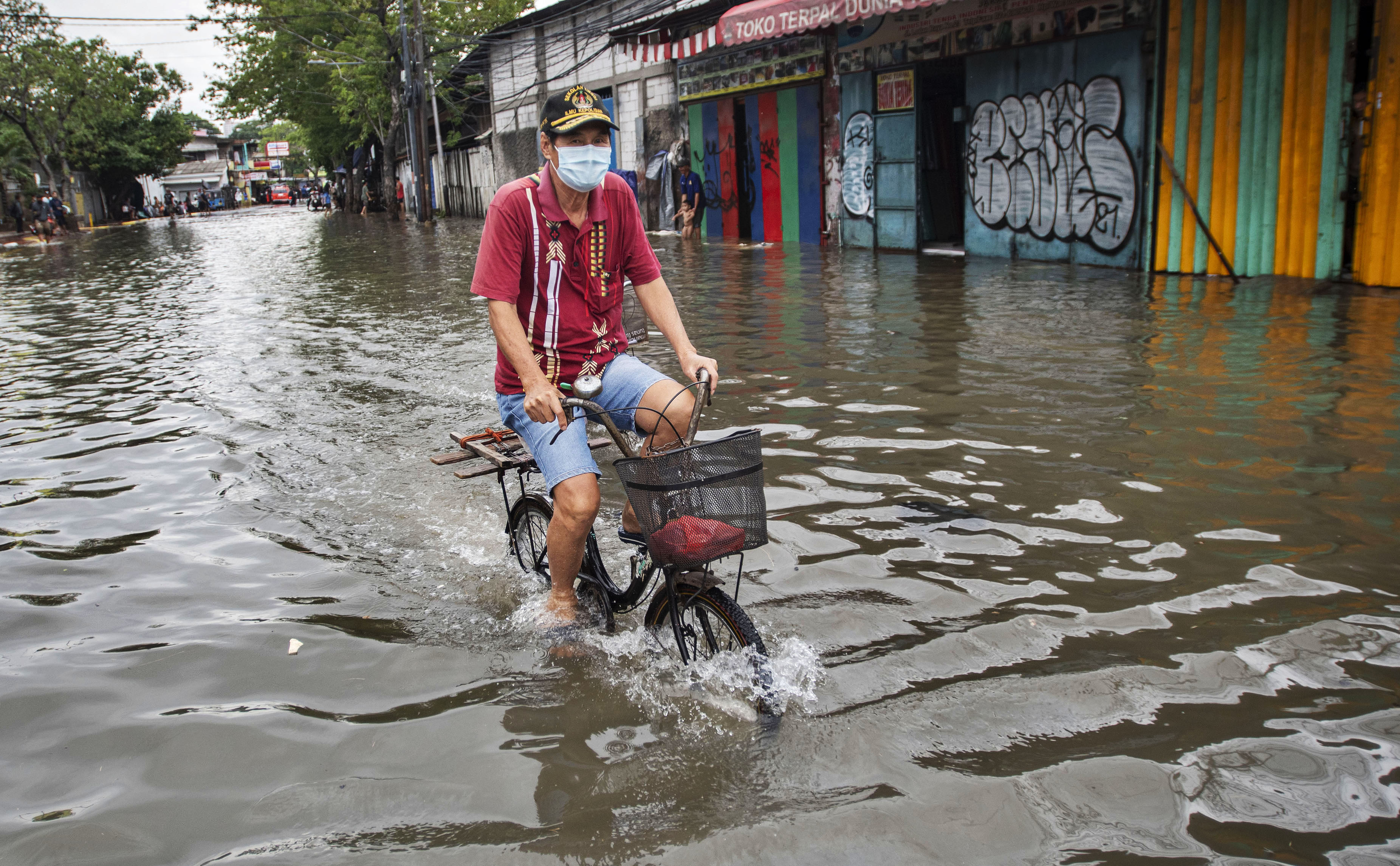 Pengendara sepeda melintasi Jalan Lodan Raya yang terendam banjir pasang air laut atau rob di Ancol, Pademangan, Jakarta.