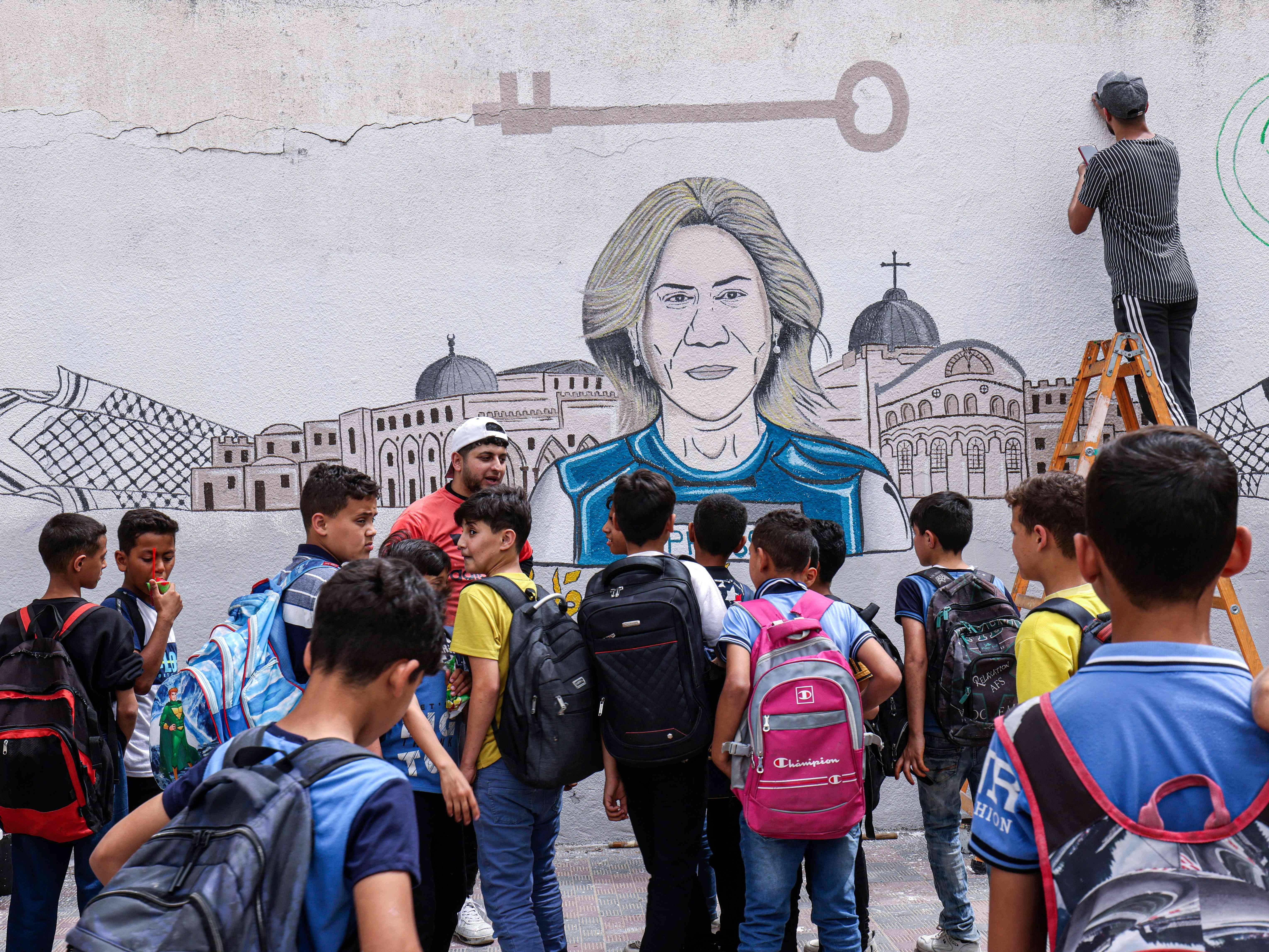 Anak-anak sekolah menyaksikan seniman Palestina melukis mural untuk menghormati jurnalis Al-Jazeera yang terbunuh, Shireen Abu Akleh.