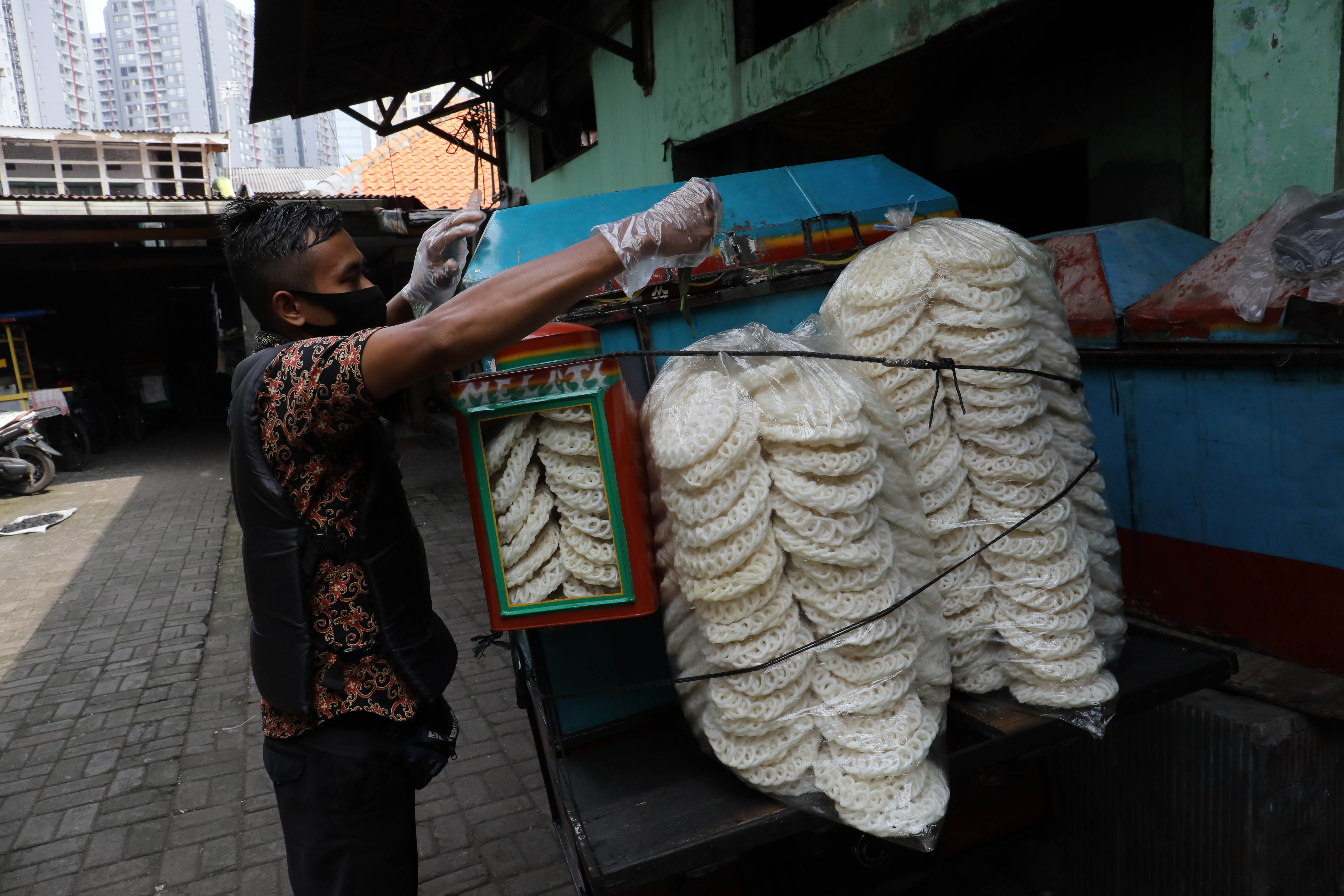 Pedagang mempersiapkan kerupuk kaleng eceran untuk dikirim ke penjual ecerean di pabrik pembuatan kerupuk kawasan Menteng Atas, Jakarta.