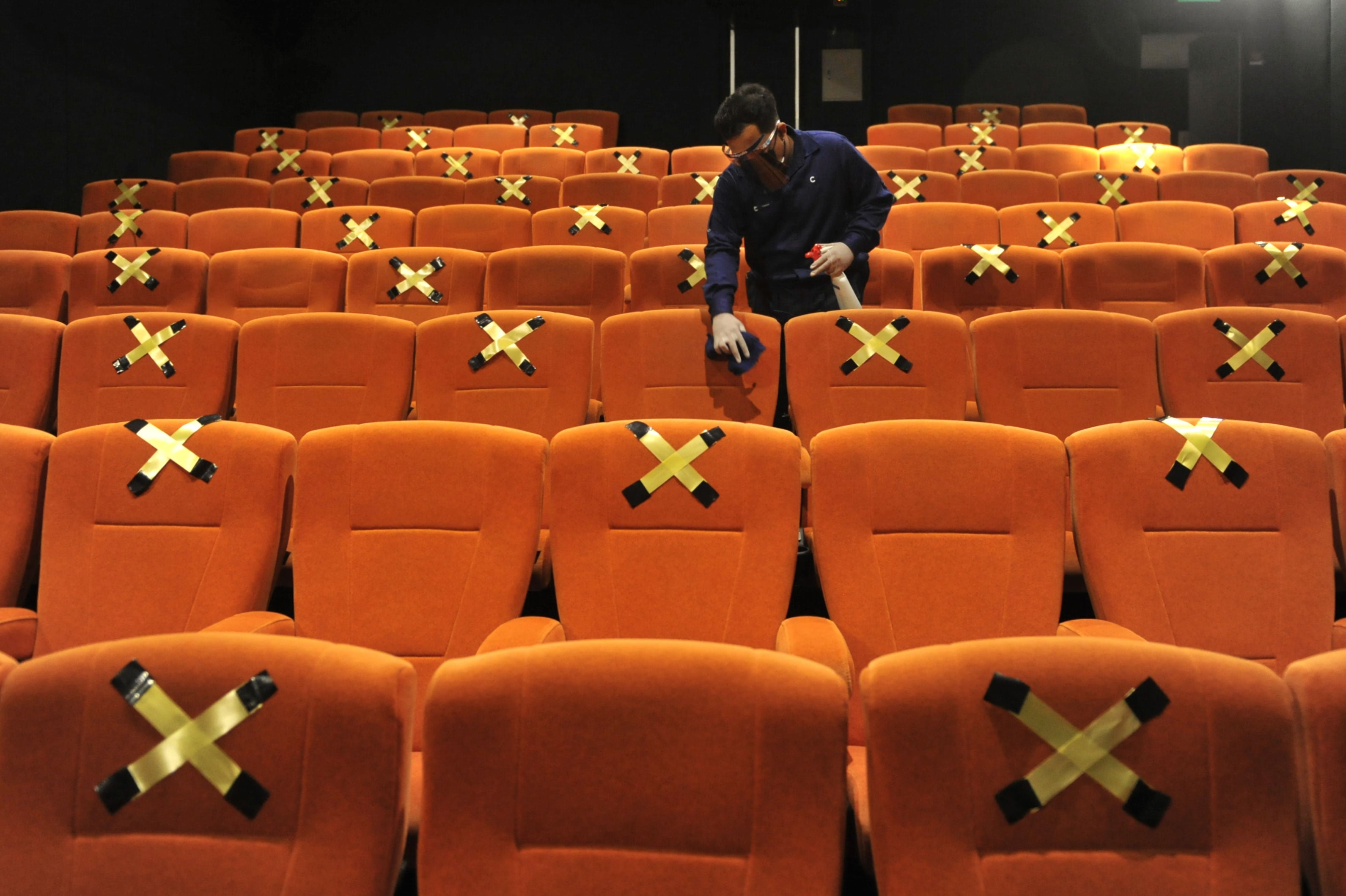 Petugas membersihkan bangku bioskop