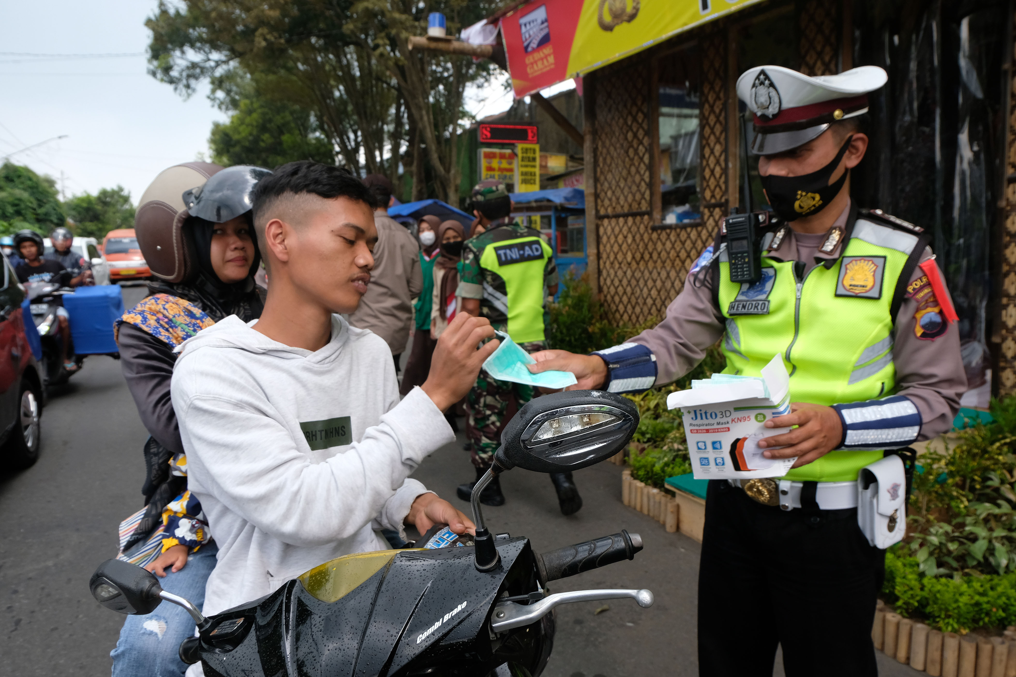 Polisi membagikan masker saat mengatur arus lalu lintas di jalur mudik di jalan utama kotaTemanggung, Jawa Tengah.