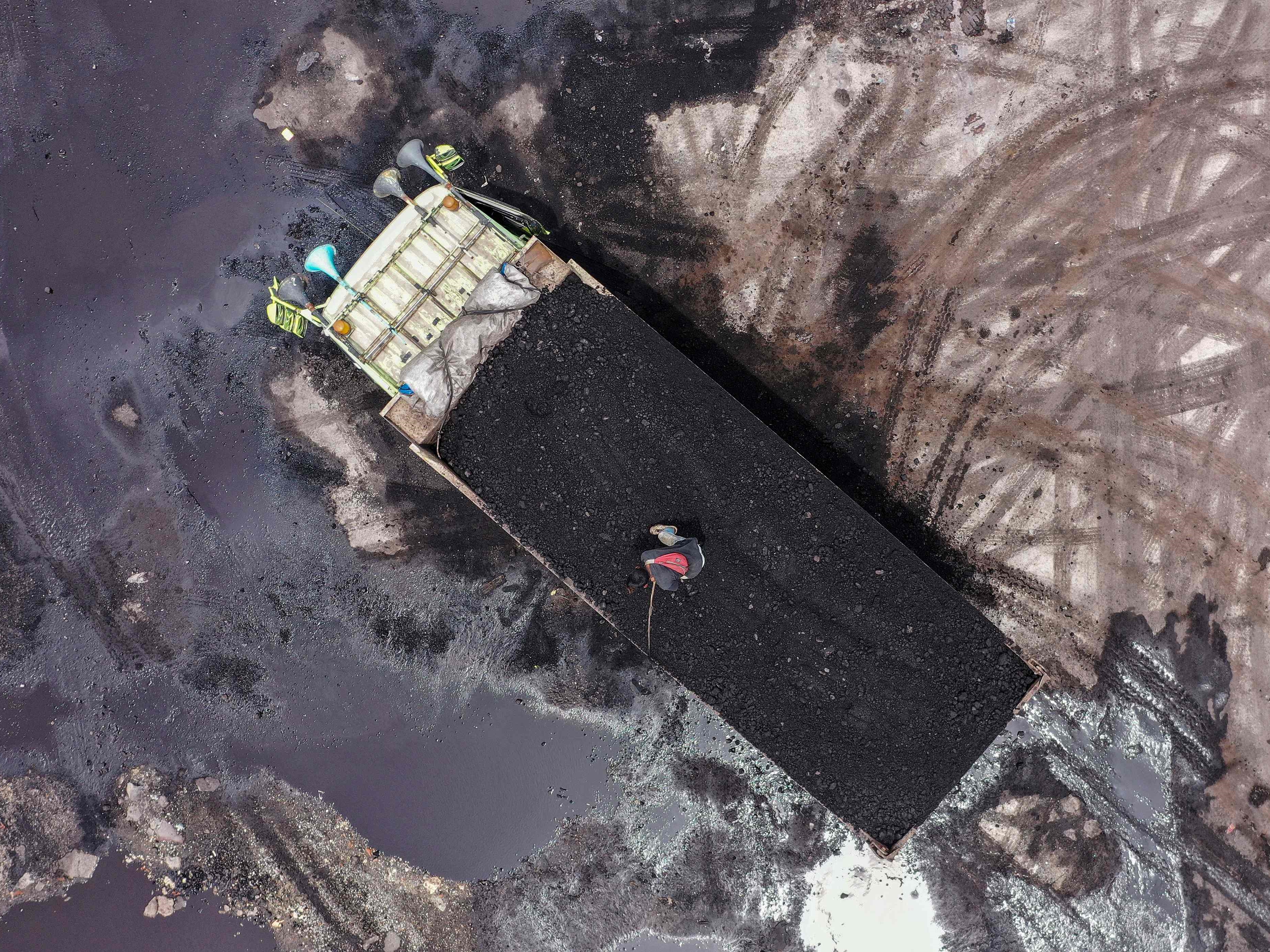 Gambar udara menunjukkan seorang pekerja berdiri di belakang truk bermuatan batu bara di Pelabuhan Karya Citra Nusantara (KCN) Marunda.