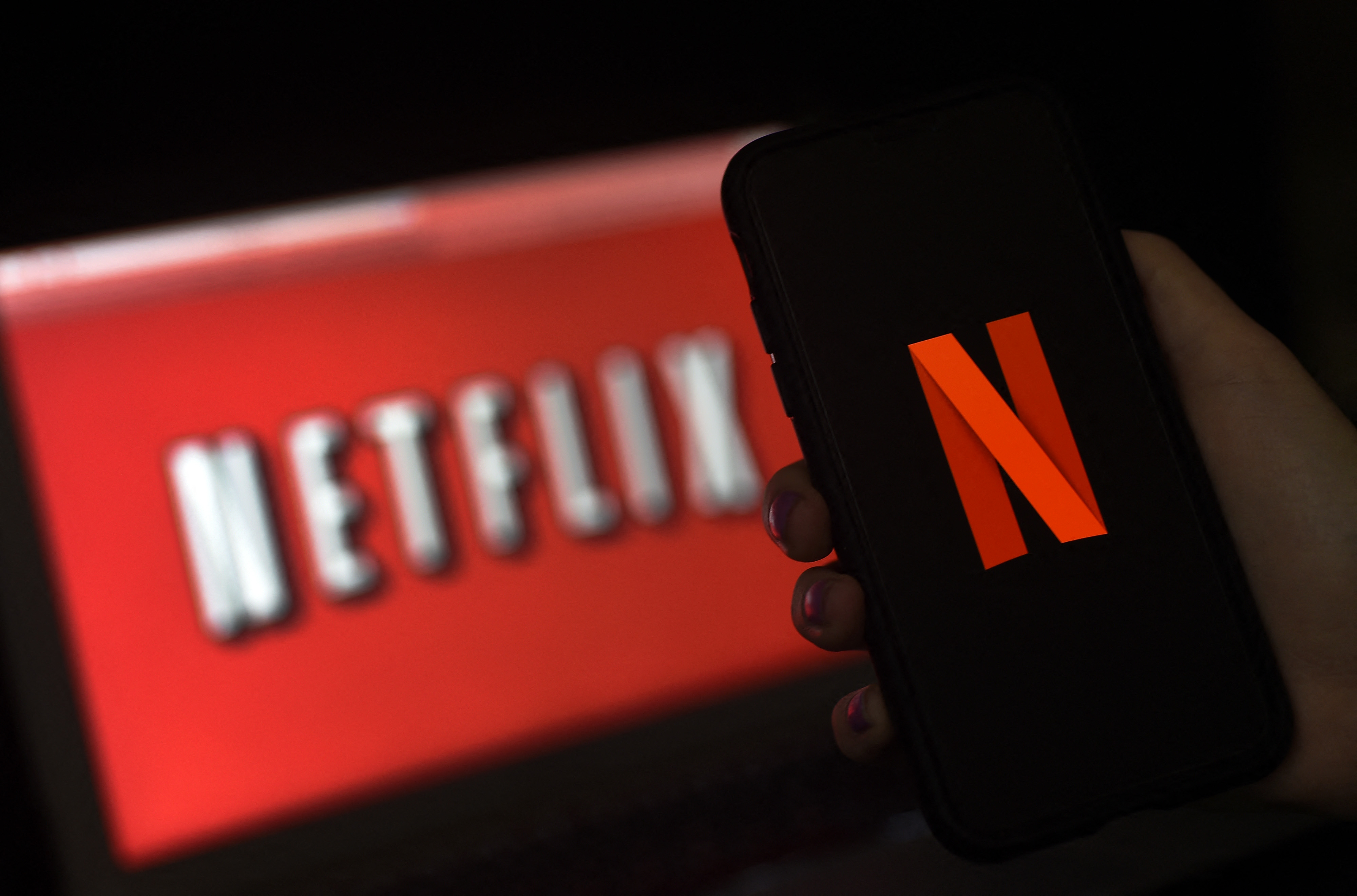 Logo Netflix terlihat di layar komputer dan ponsel.