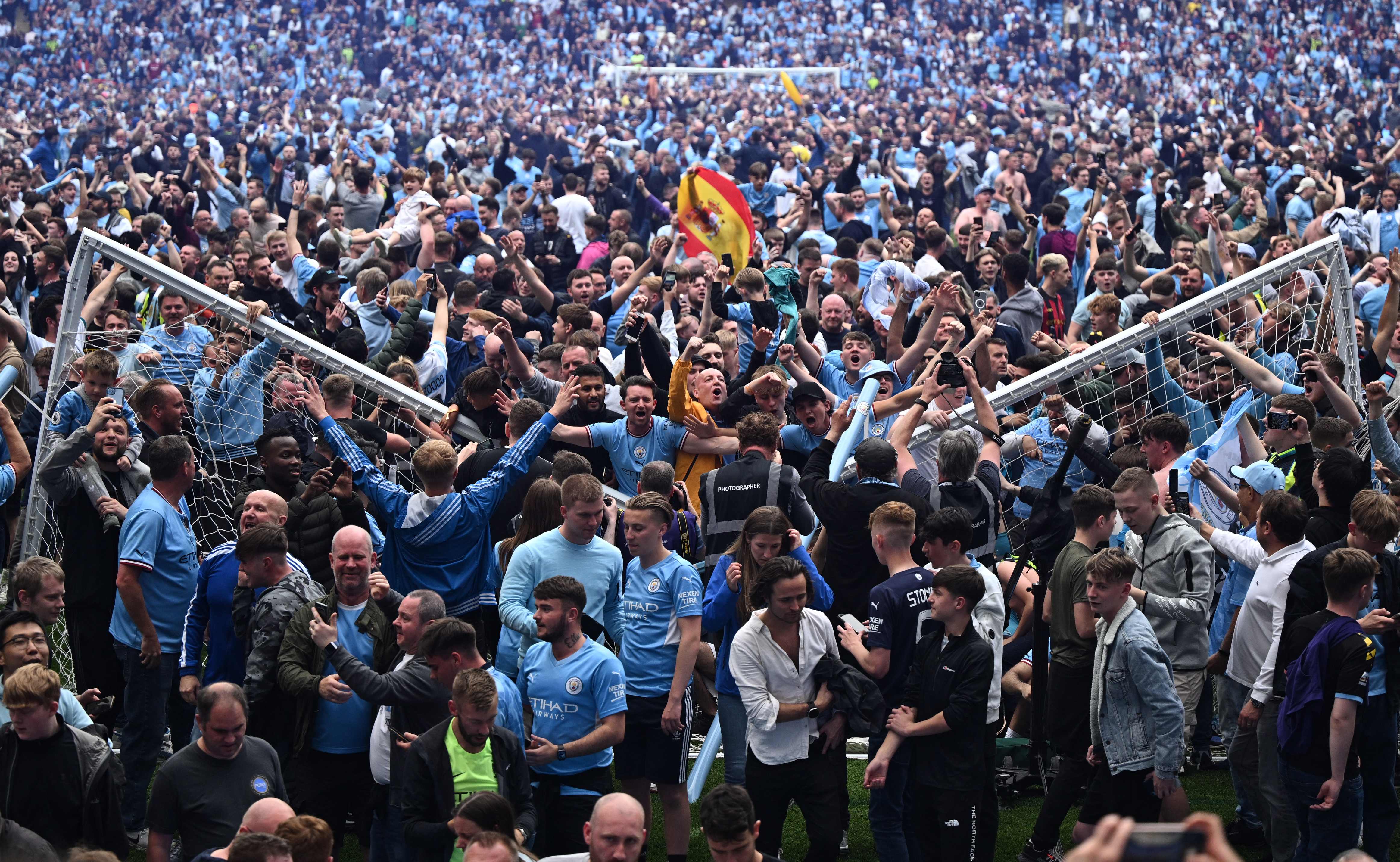 Pendukung Manchester City menyerbu masuk lapangan usai tim mereka menjadi juara Liga Primer Inggris, Minggu (22/5).