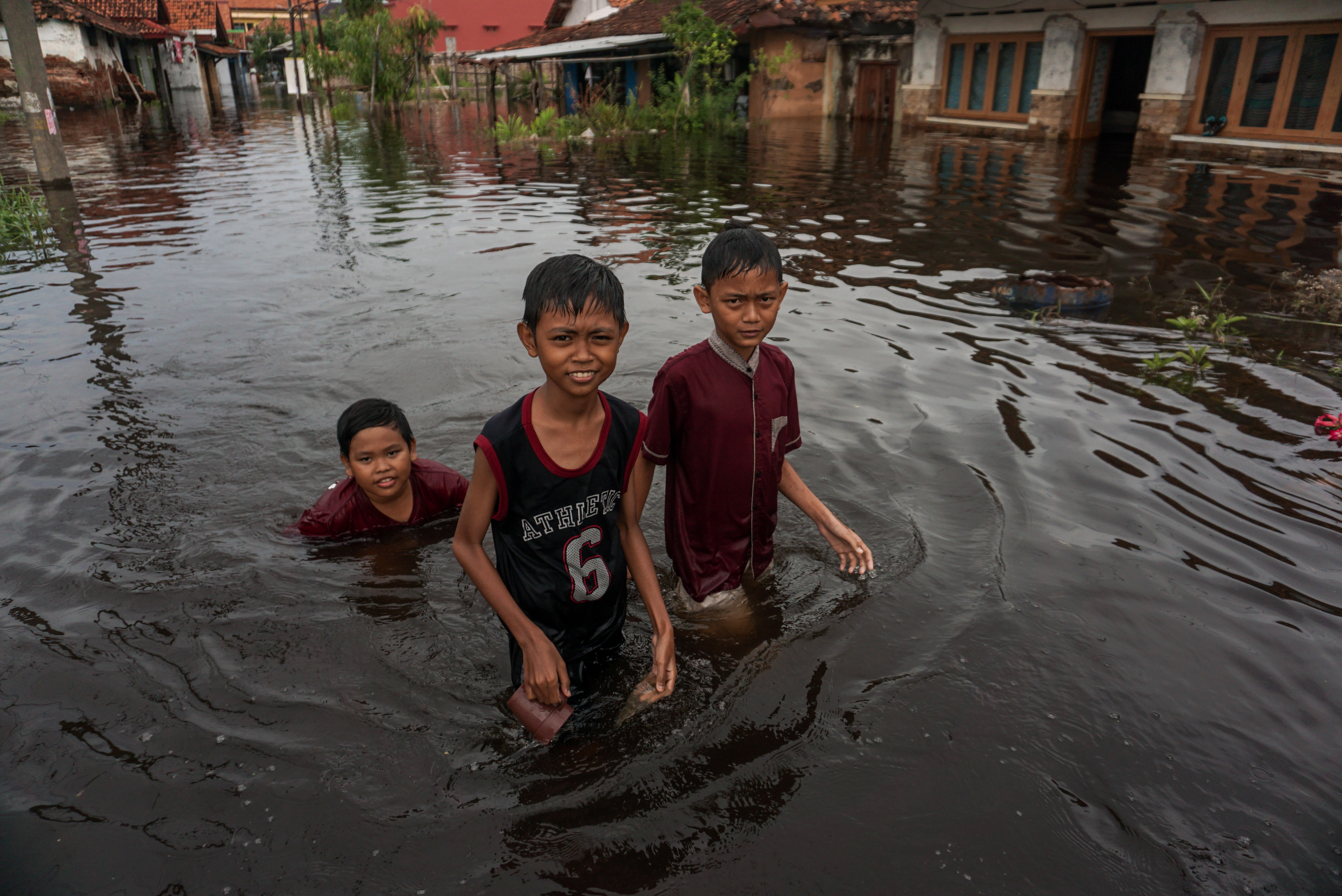 Sejumlah anak berjalan melewati banjir rob di wilayah Pekalongan, Jawa Tengah.