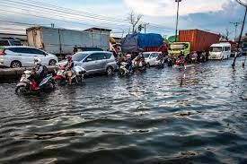 Kendaraan bermotor menembus jalan raya pantura Demak KM 8 ruas Demak-Semarang yang terendam limpasan air laut ke daratan (rob) di Demak.