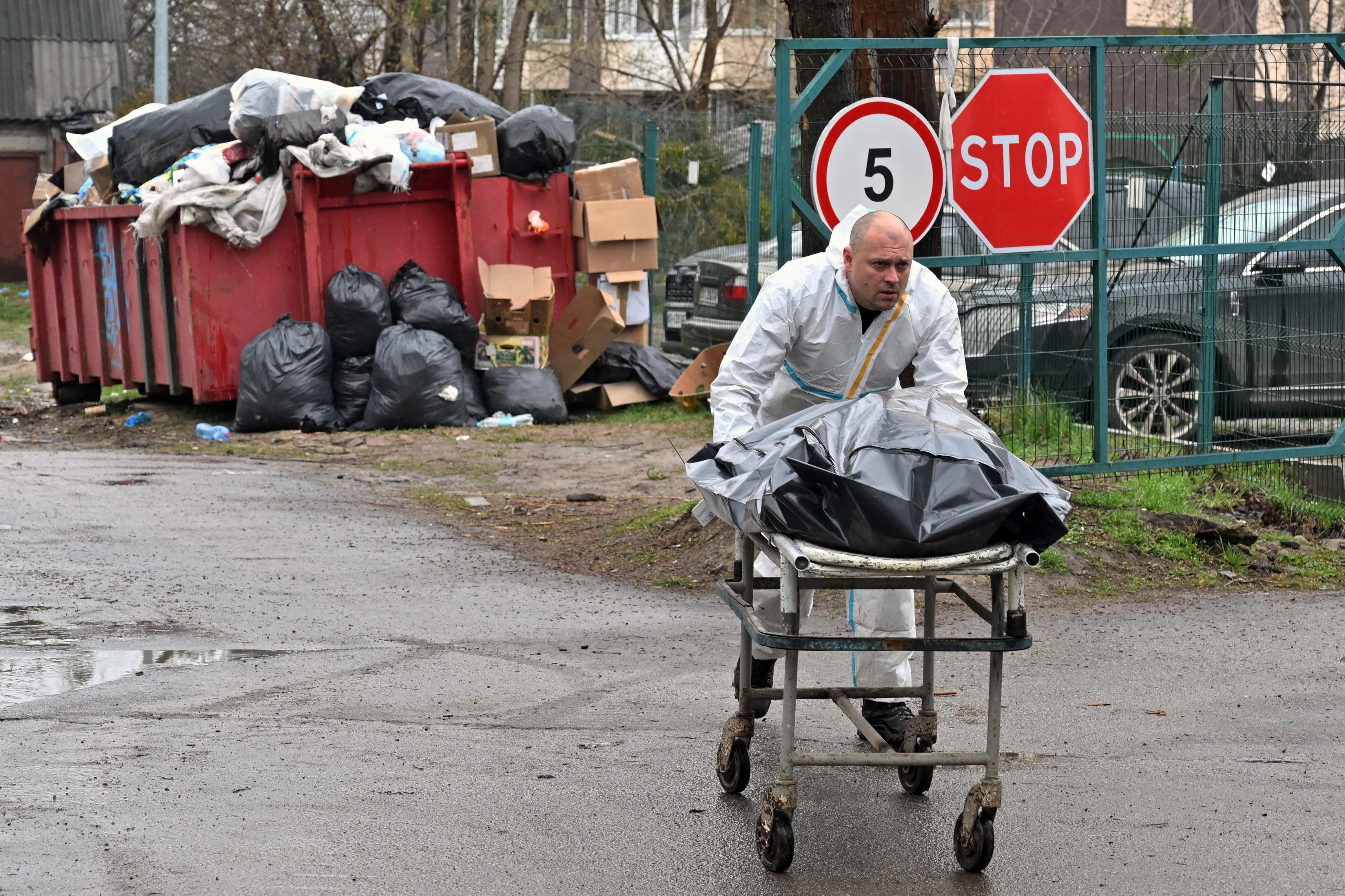 Seorang petugas membawa kantung jenazah yang isinya akan diidentifikasi di Bucha, Ukraina.