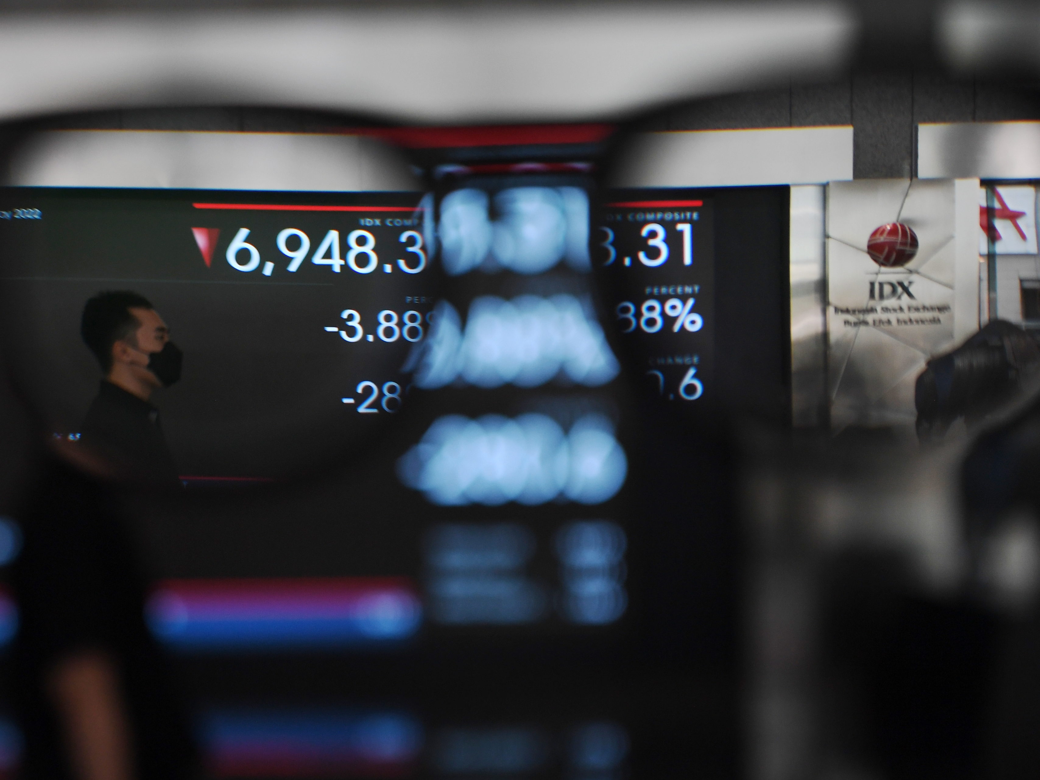 Pekerja melintas di depan layar yang menampilkan pergerakan Indeks Harga Saham Gabungan di Bursa Efek Indonesia, Jakarta, Senin (9/5).