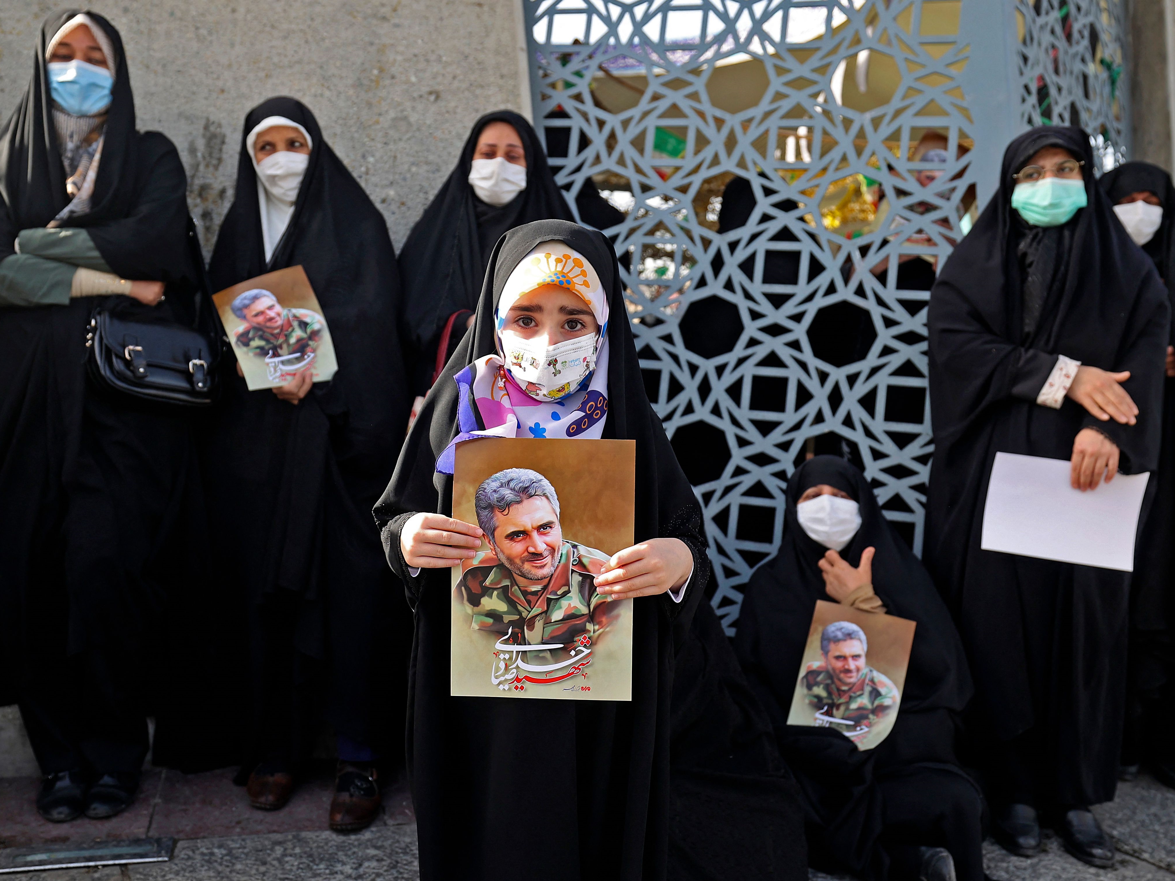 Wanita Iran mengangkat potret kolonel Pengawal Revolusi Sayyad Khodai selama prosesi pemakamannya di alun-alun Imam Hussein di Teheran.
