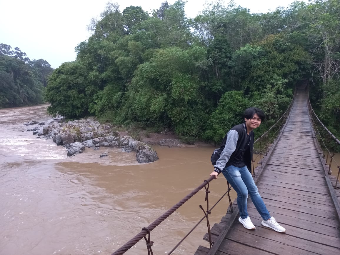 Seorang remaja wisatawan sedang berpose di tengah jembatan gantung yang menjadi salah satu spot menarik kawasan Geopark Merangin, Jambi.