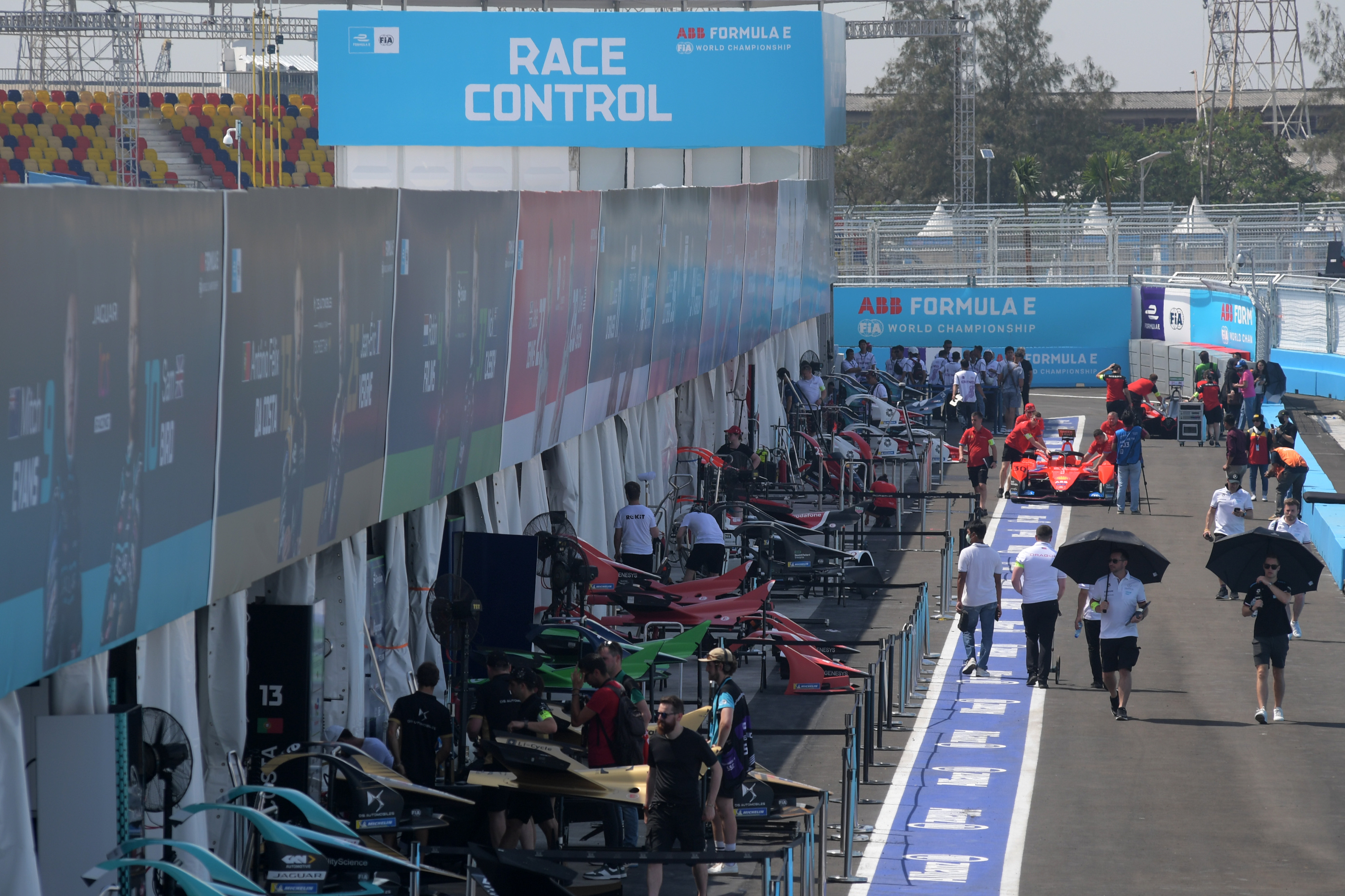 Para kru memeriksa mobil balap listrik di pit lane Jakarta International E-Prix Circuit.