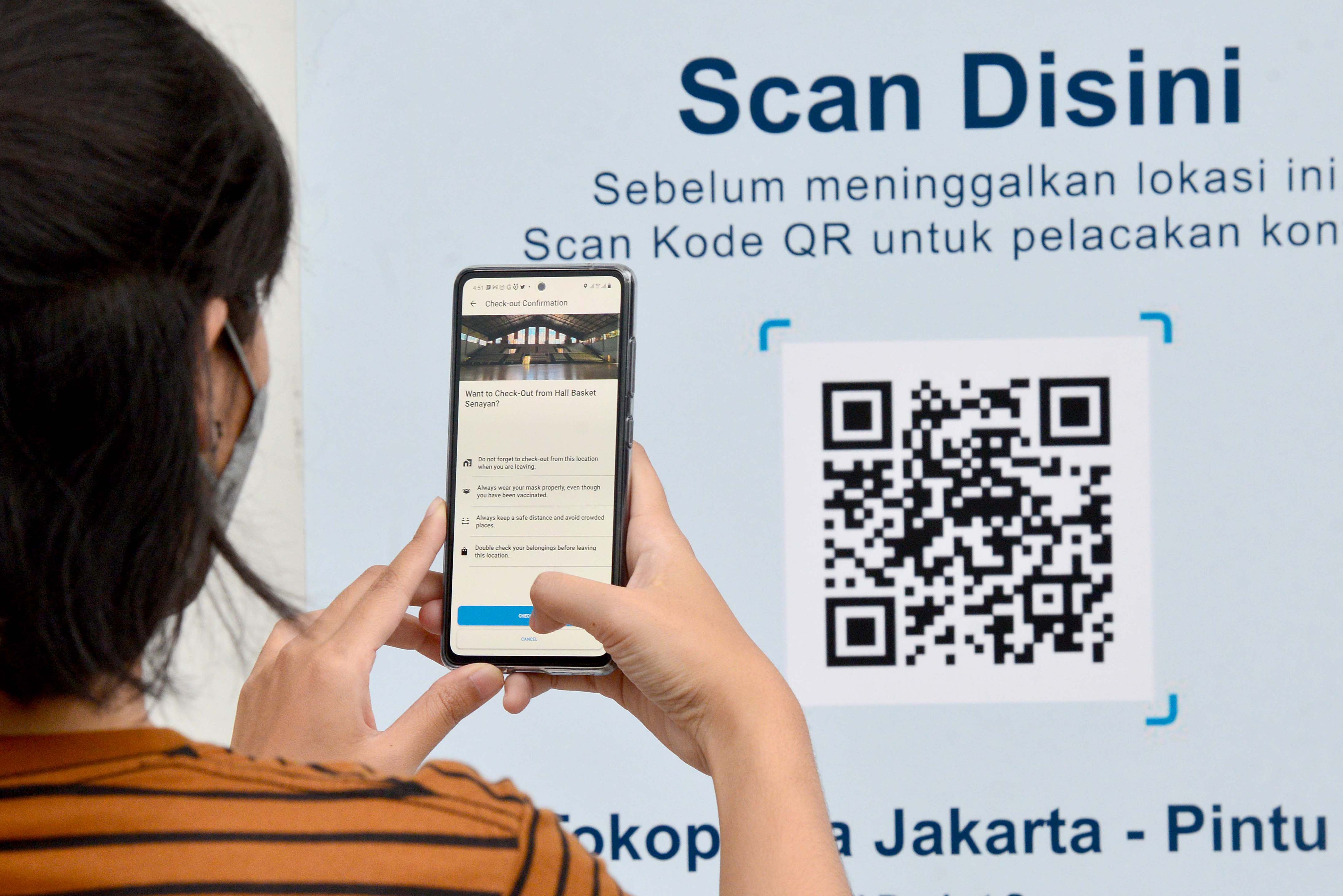 warga melakukan pemindaian aplikasi PeduliLindungi sebelum masuk dalam ruangan