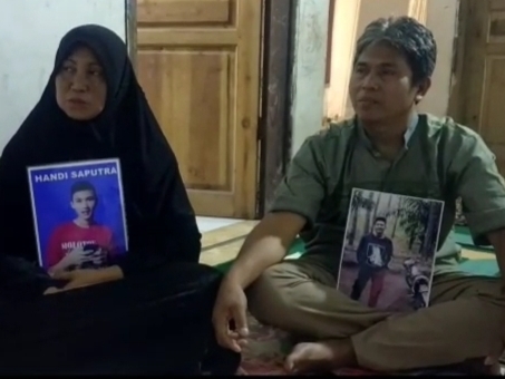 Etes Hidayatulah dan Suryati memegang foto anaknya Hendi Saputra.