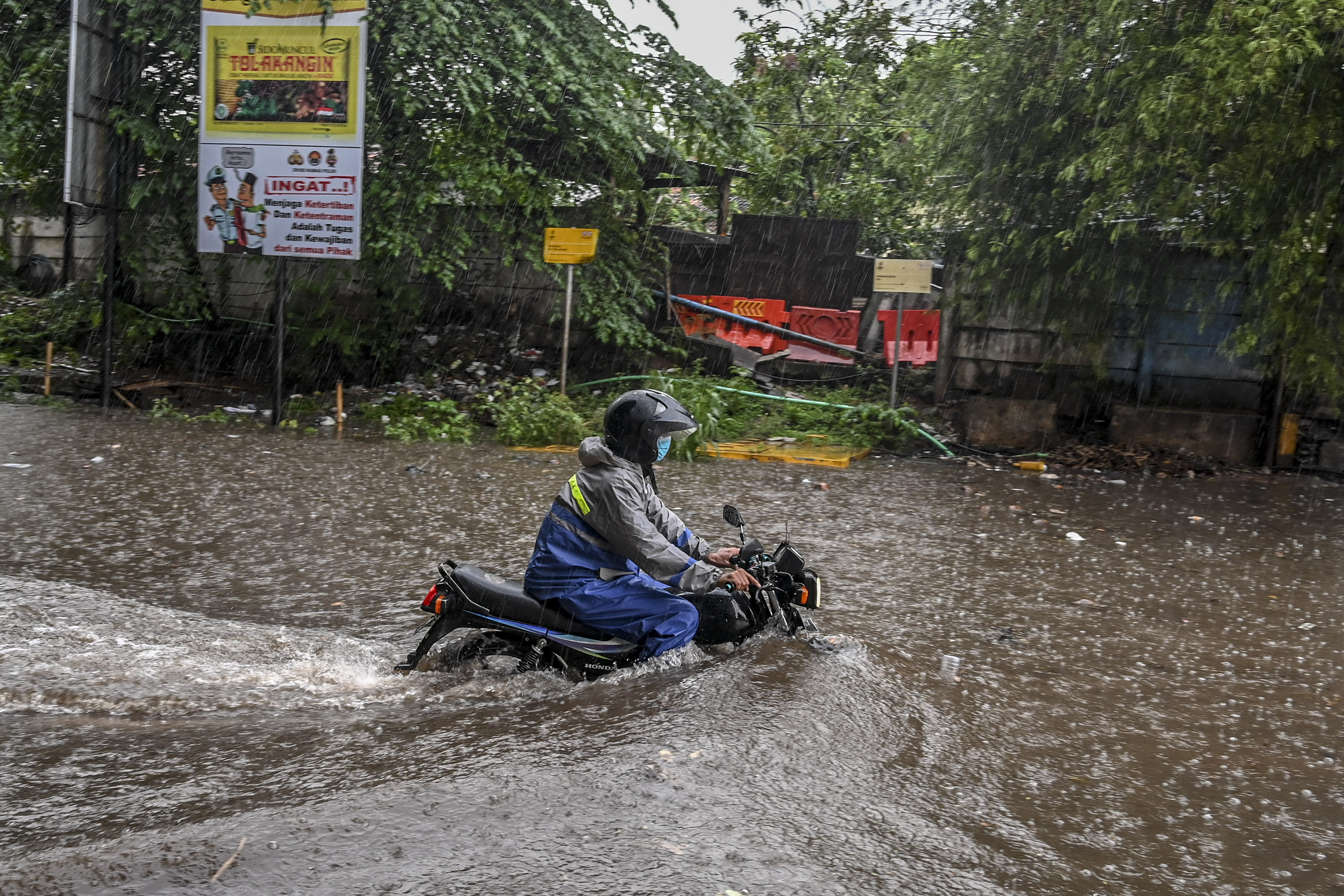 Pengendara motor melintasi banjir di kawasan Jalan Akses Tol Cibitung, Jawa Barat.
