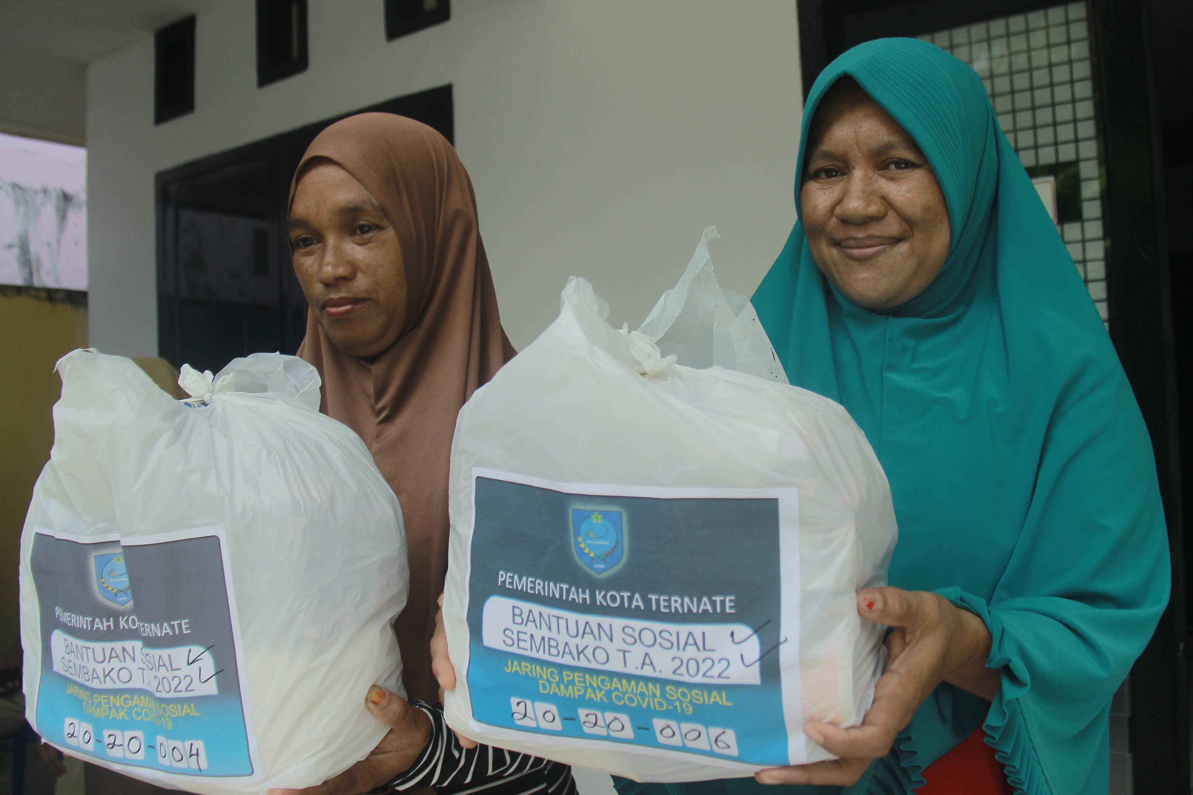 Dua warga menunjukan paket sembako yang diterima di Kantor Kelurahan Ngade, Kota Ternate, Provinsi Maluku Utara, Selasa (7/6/2022)