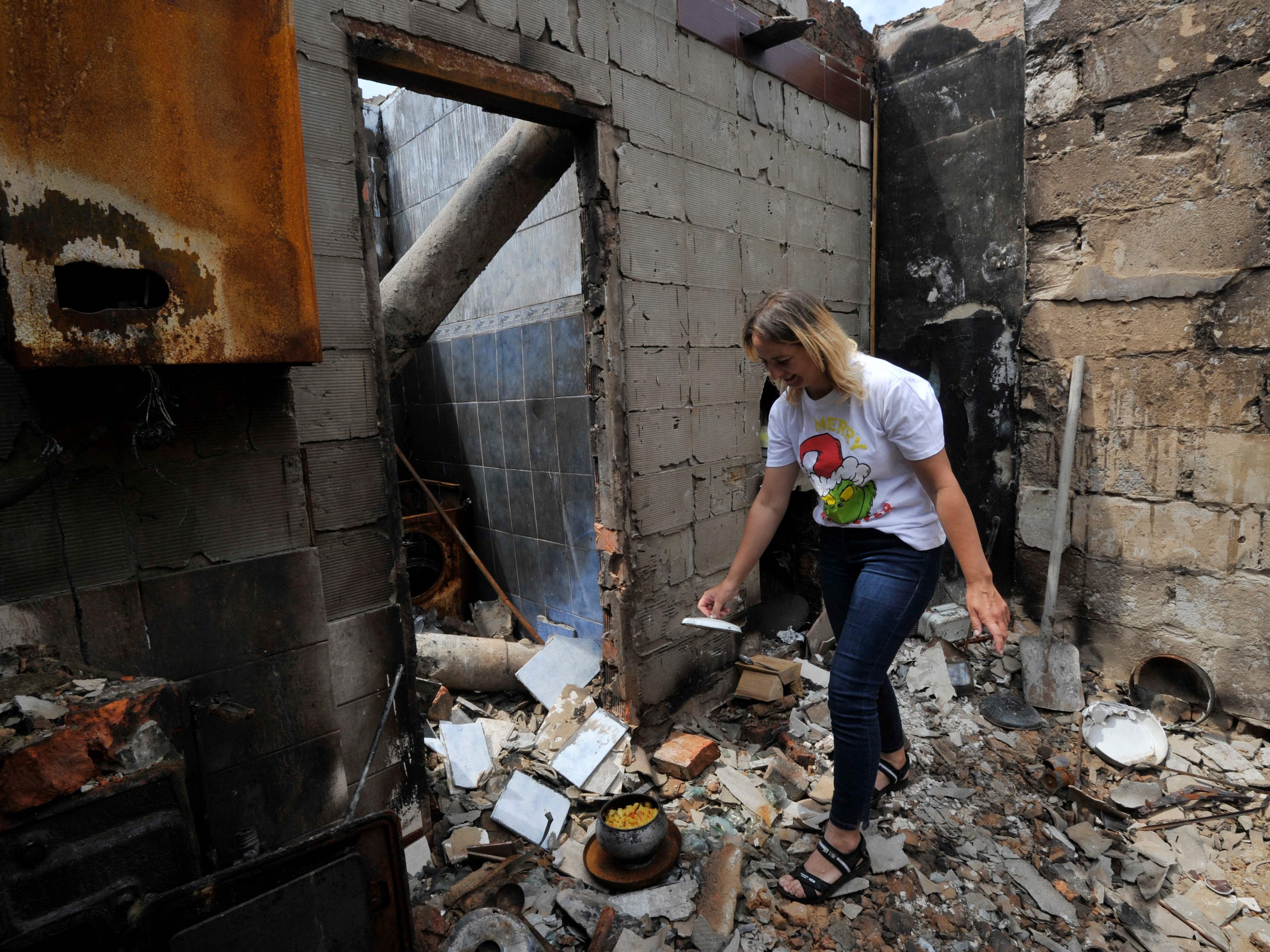 Irina, 35, memasak keju cottage di tungku kayu yang selamat dari rumahnya yang hancur di desa Novoselivka, luar Chernigiv, 21 Juni 2022.