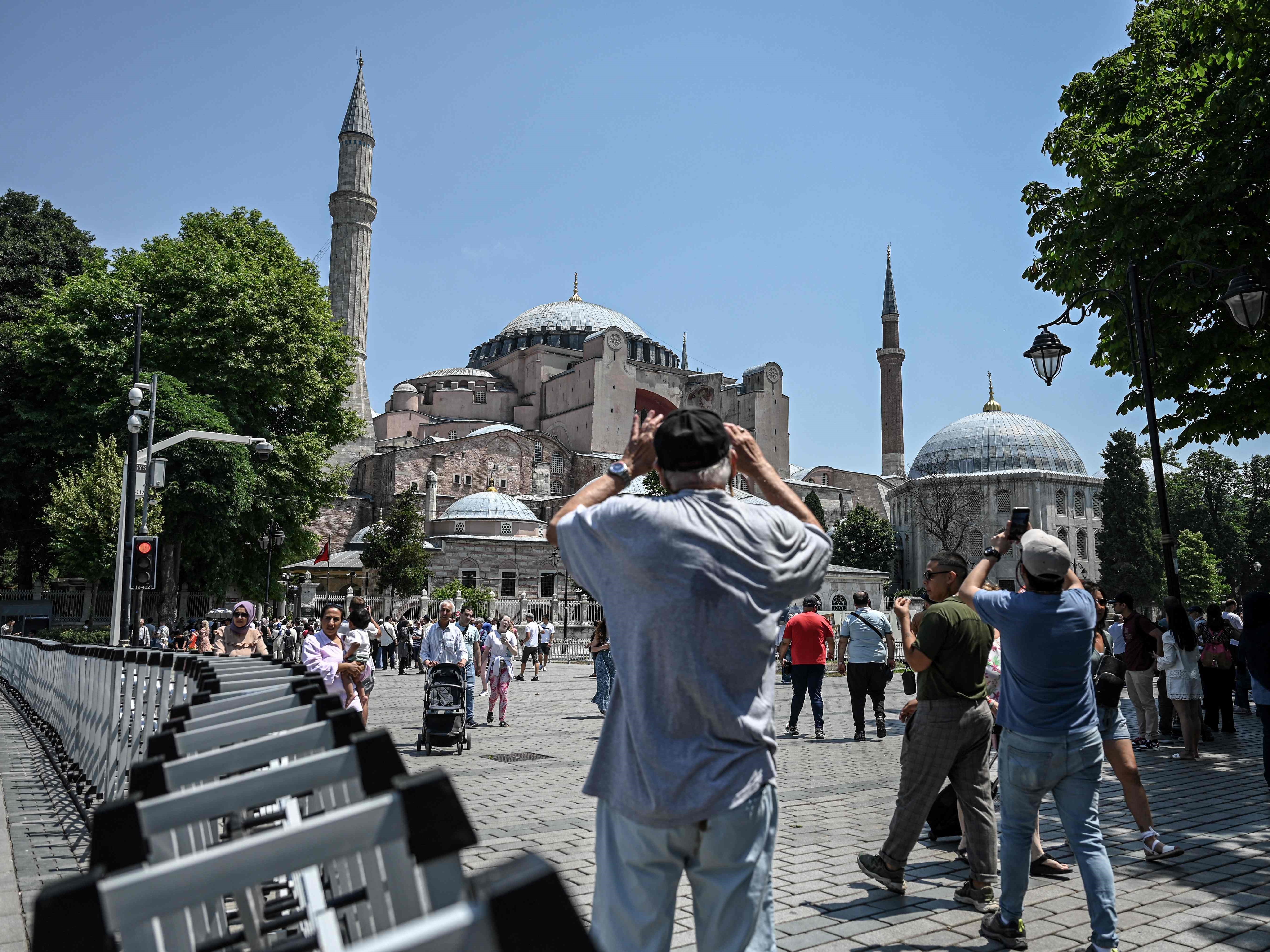 Turis mengambil gambar Masjid Hagia Sophia sambil berdiri di samping pagar polisi di Istanbul, pada 14 Juni 2022.