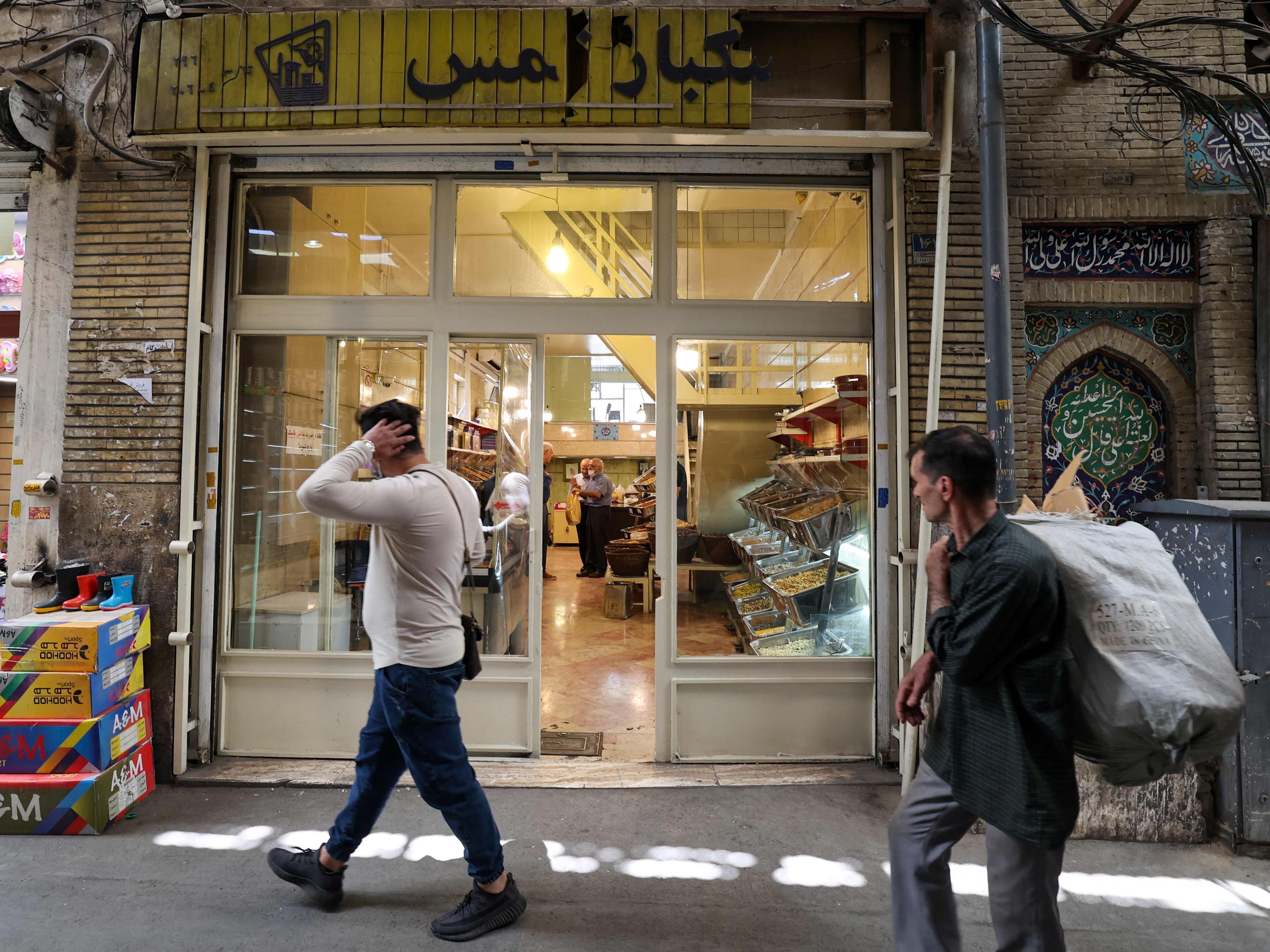 Orang-orang berjalan melewati pedagang grosir pistachio tertua di Iran di Graz Bazaar yang terkenal di Teheran pada 19 Juni 2022.