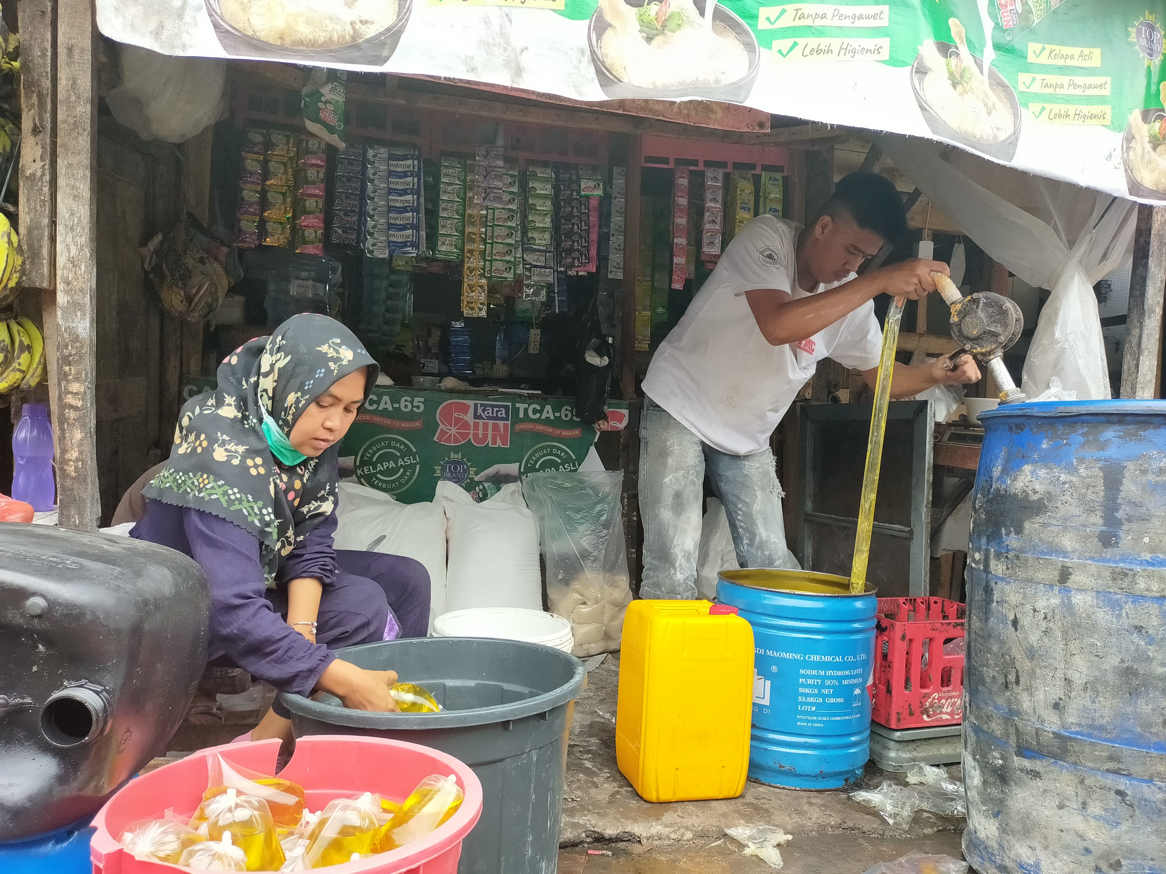 Pedagang menakar minyak goreng curah di toko mereka di Tasikmalaya, Jawa Barat, Rabu (8/6).