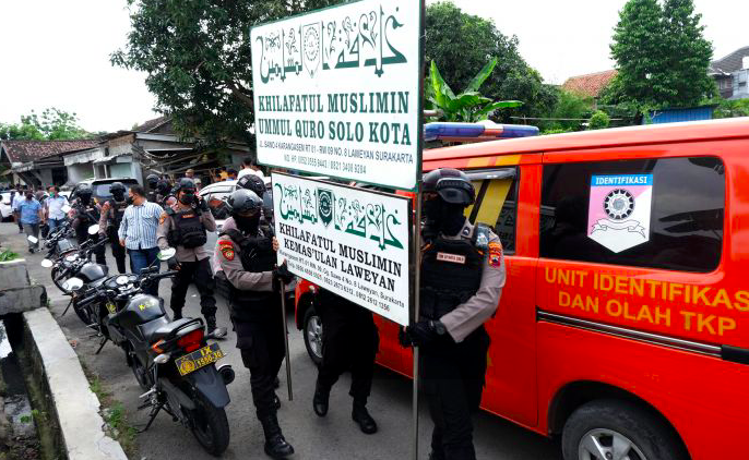 Polisi menurunkan papan bertulis Khilafatul Muslimin dari rumah warga sekaligus kantor cabang kelompok tersebut di Solo, Jawa Tengah.