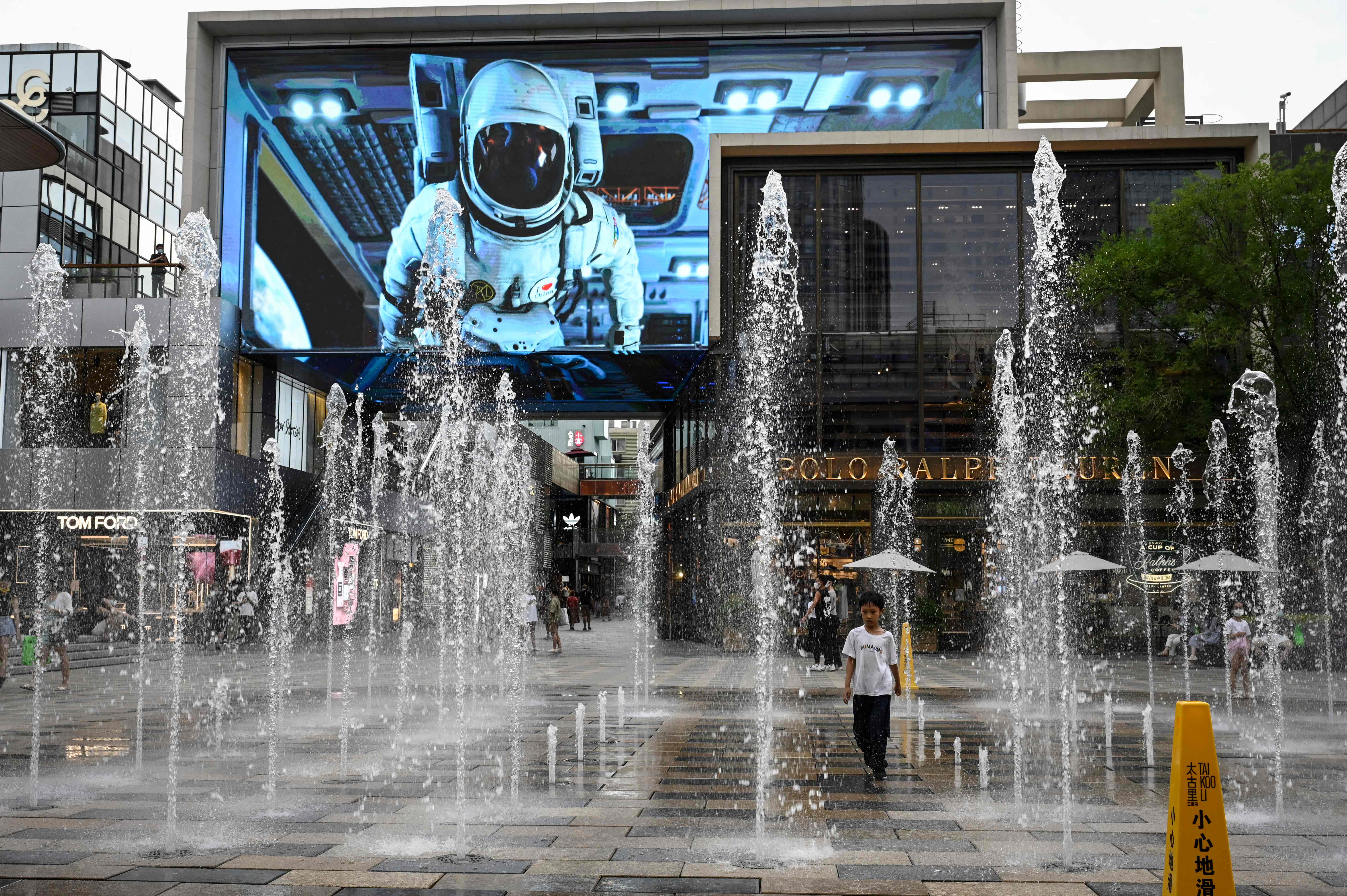 Seorang anak bermain di taman air mancur sebuah mal di pusat Kota Beijing, Tiongkok, yang sepi, Selasa (28/6).