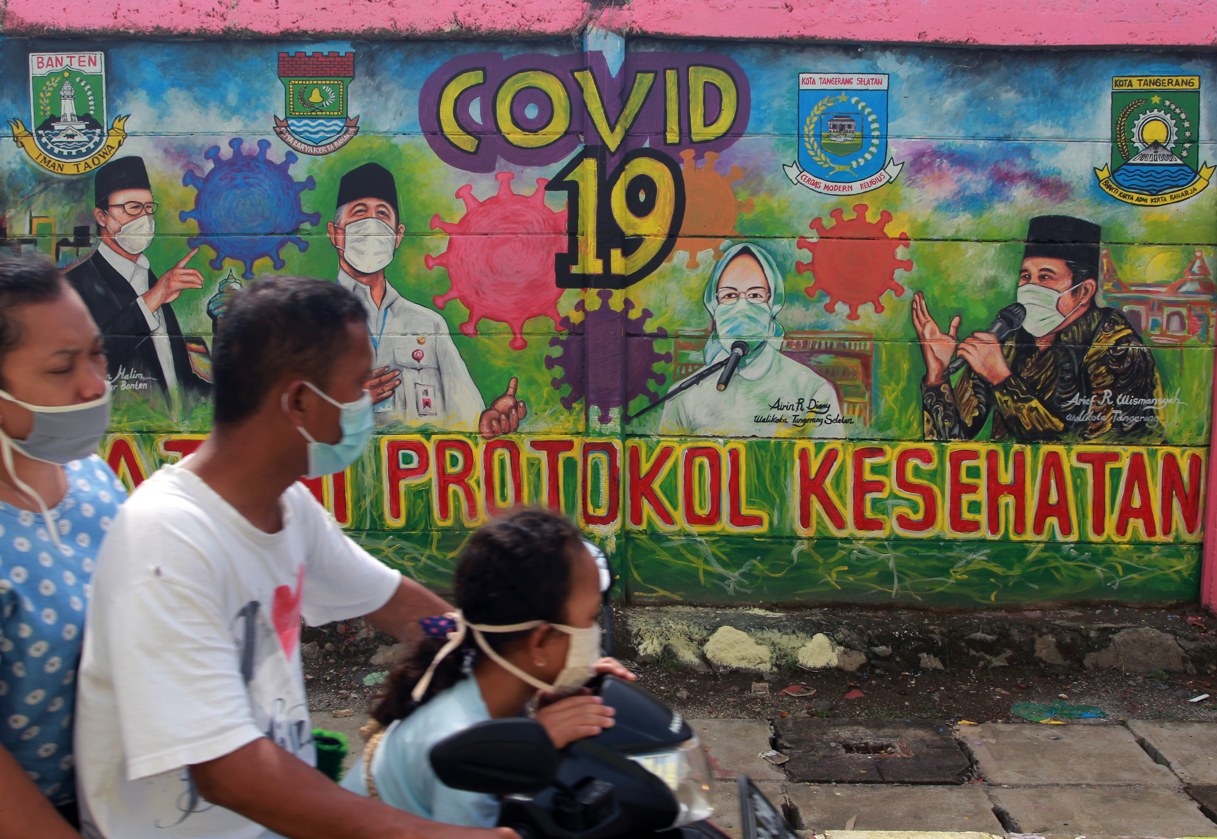 Warga melintas di depan mural bergambar tiga kepala daerah Tangerang Raya dan Gubernur Banten berisi edukasi protokol kesehatan.