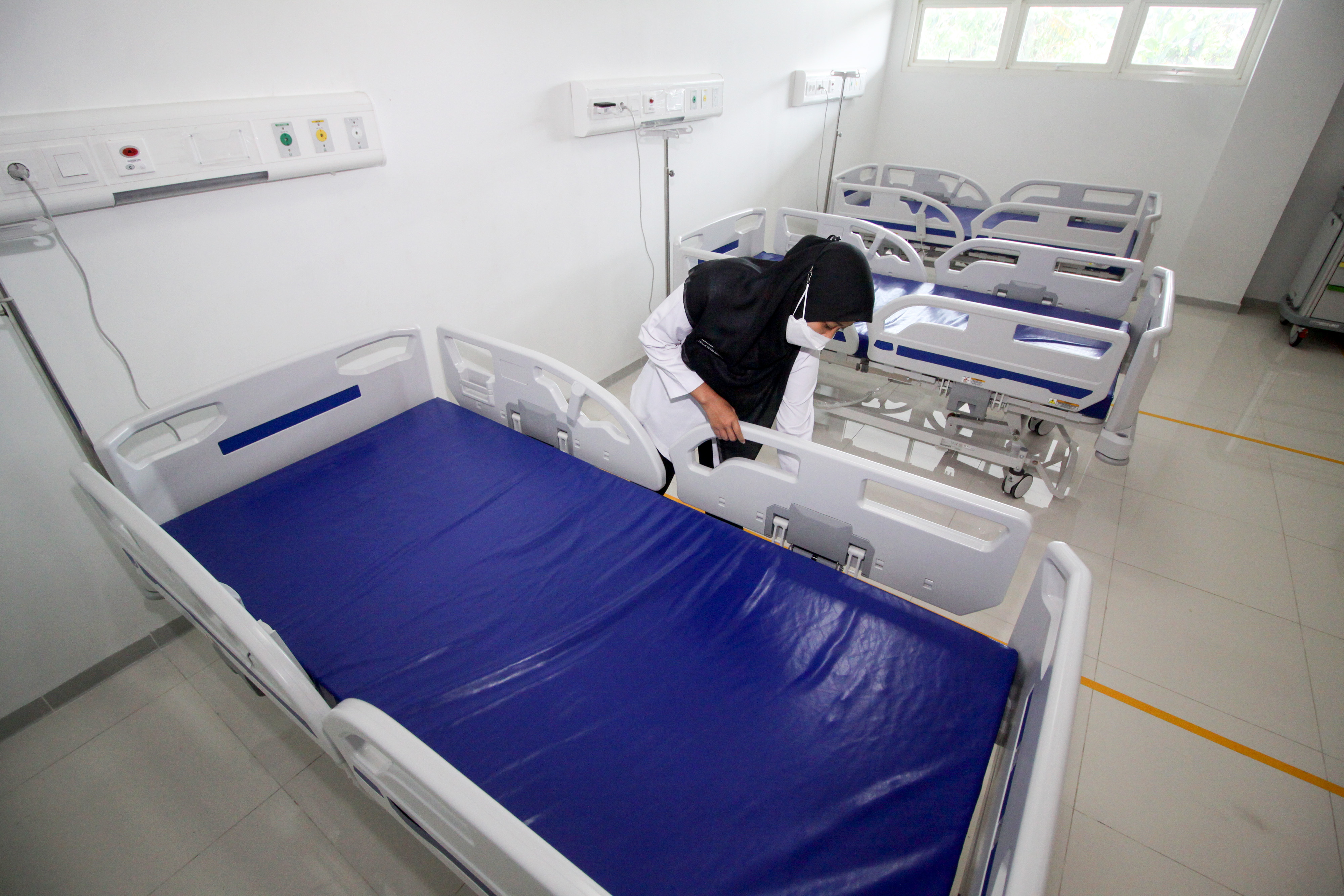 Petugas merapikan tempat tidur di rumah sakit yang baru saja dioperasikan.