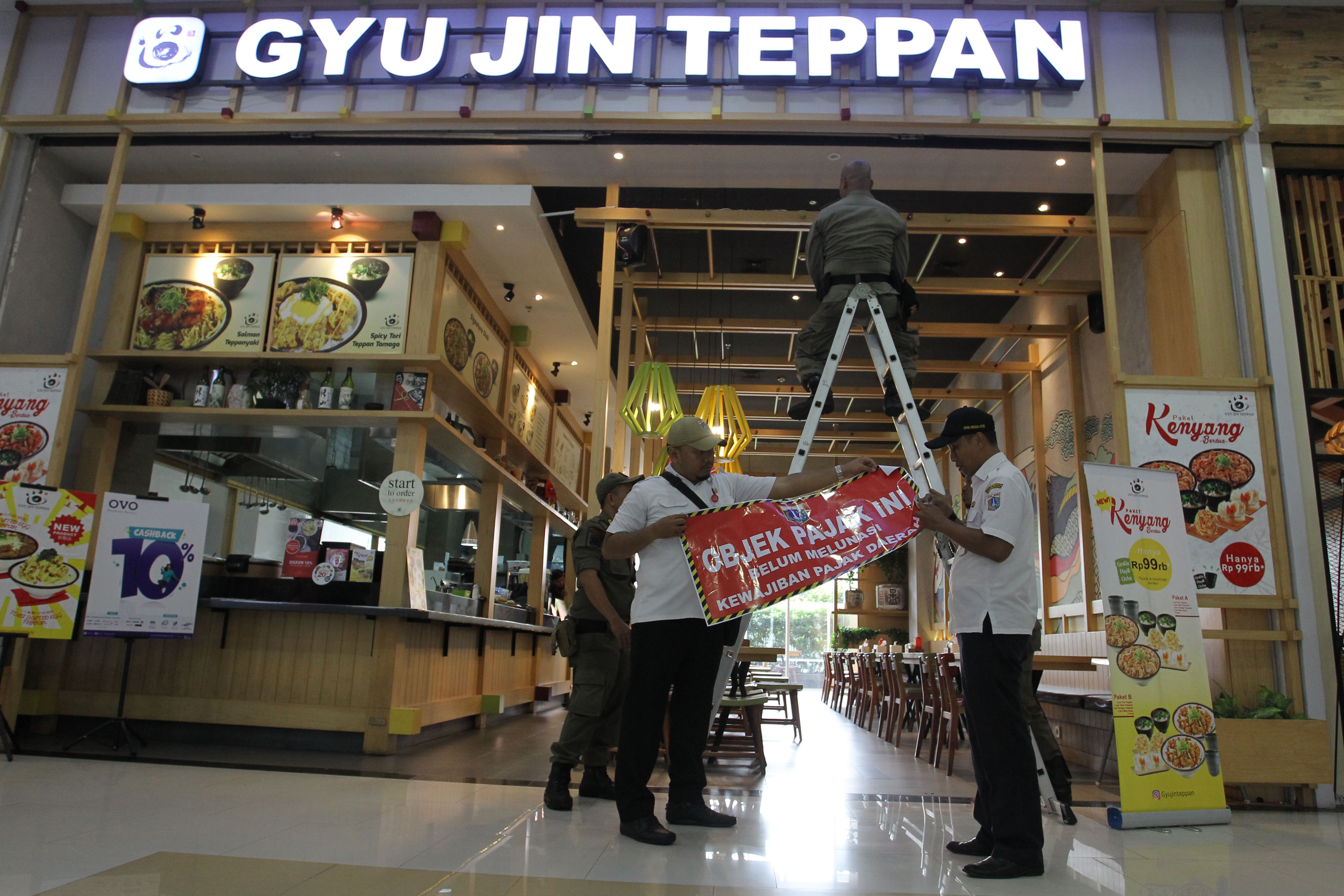 Ilustrasi pemasangan stiker di tempat usaha karena belum membayar pajak