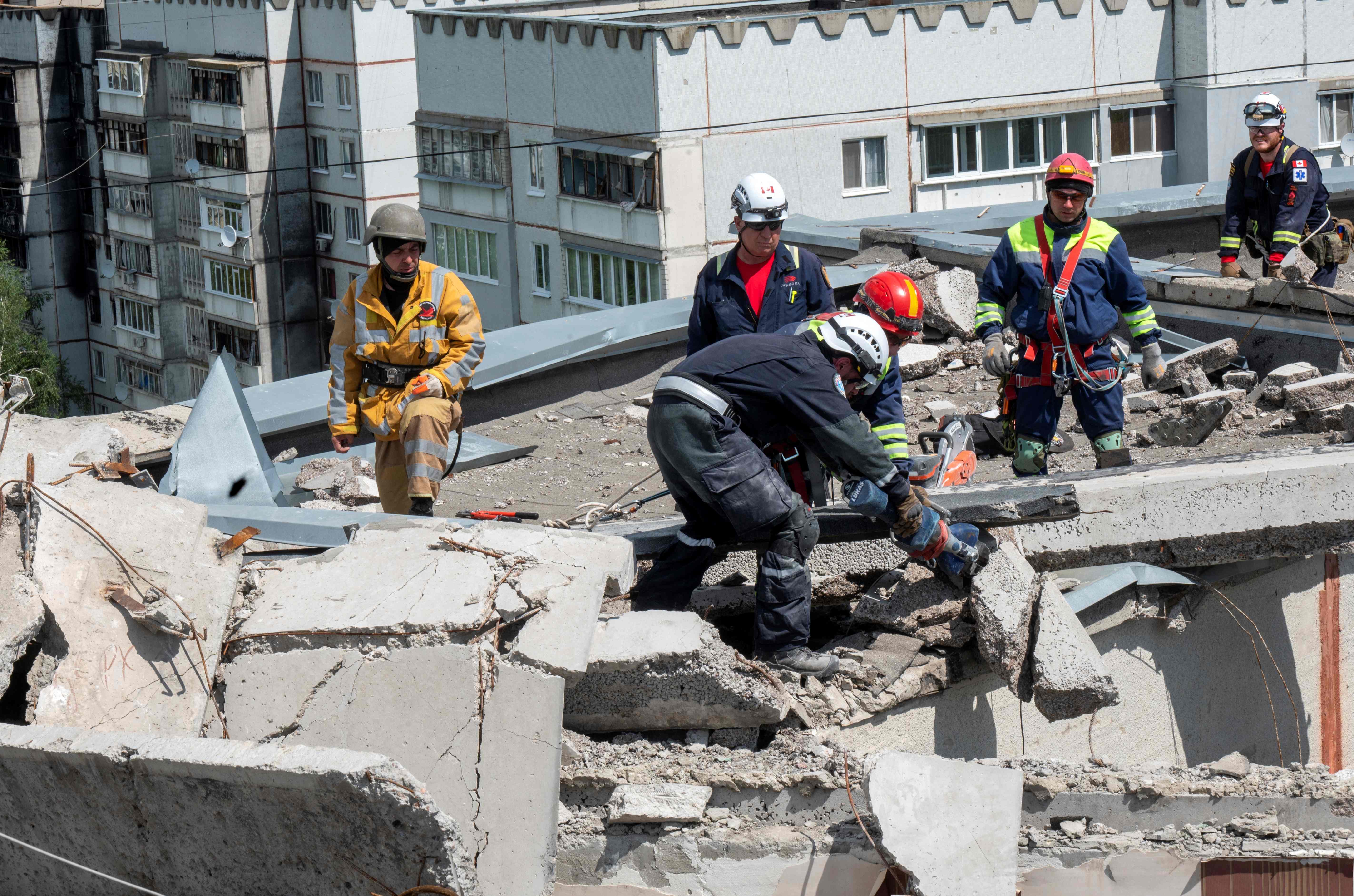 Para pekerja membersihkan reruntuhan di bangunan perumahan yang rusak dihantam serangan Rusia di Kharkiv, Ukraina.