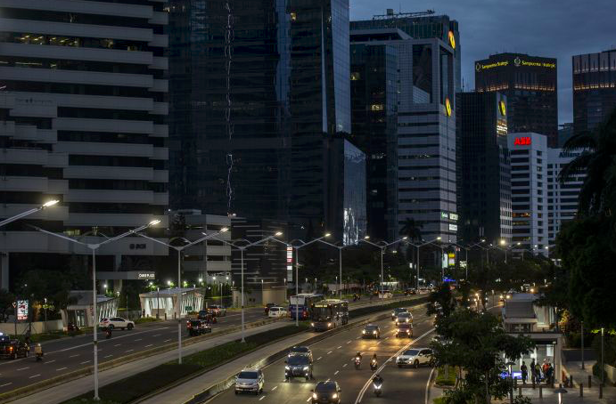 Ilustrasi - Kendaraan melintas di antara gedung bertingkat di Jakarta.
