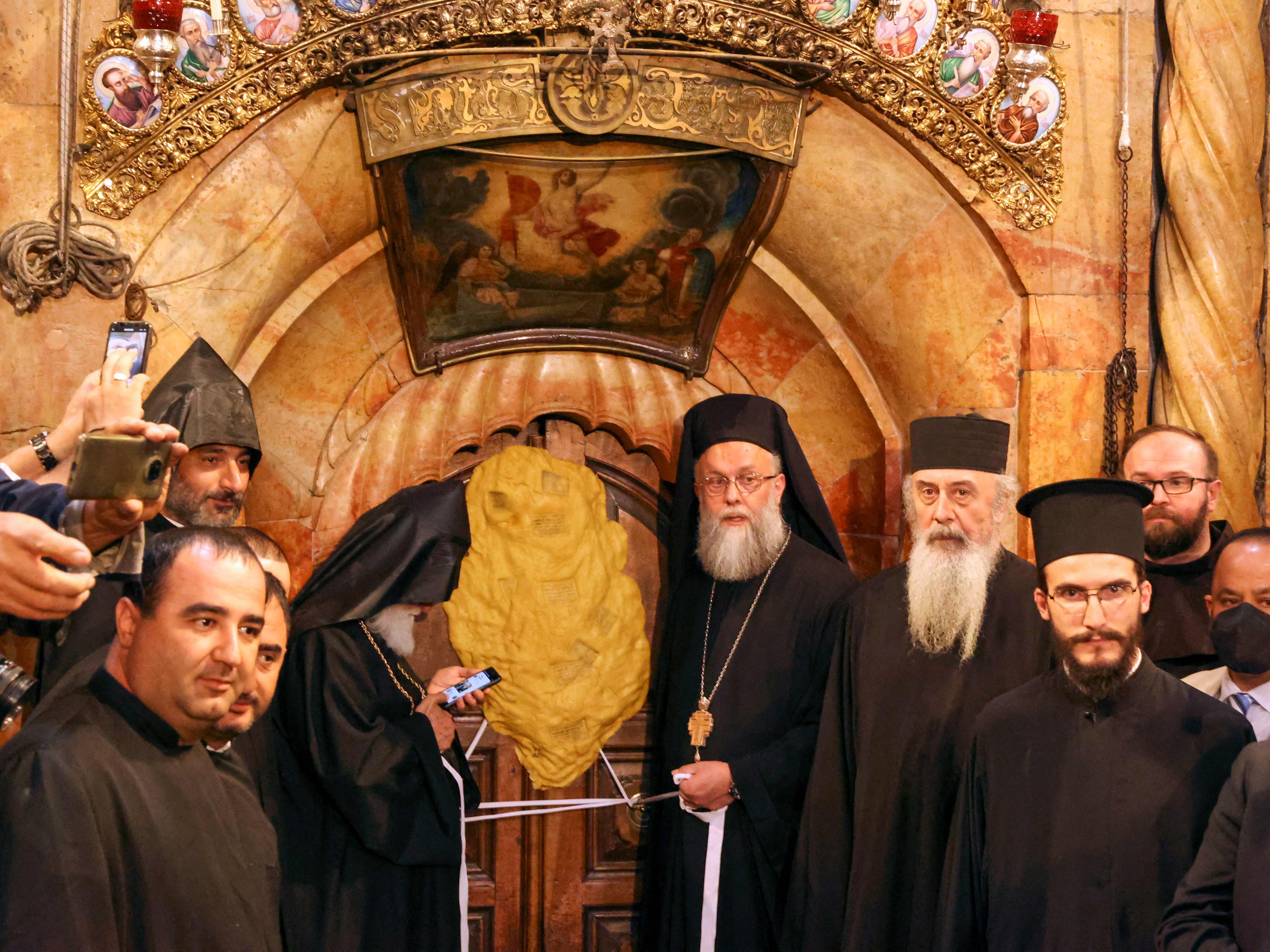 Pendeta Ortodoks berdiri di depan pintu tertutup Edicule, yang secara tradisional diyakini sebagai situs pemakaman Yesus Kristus.