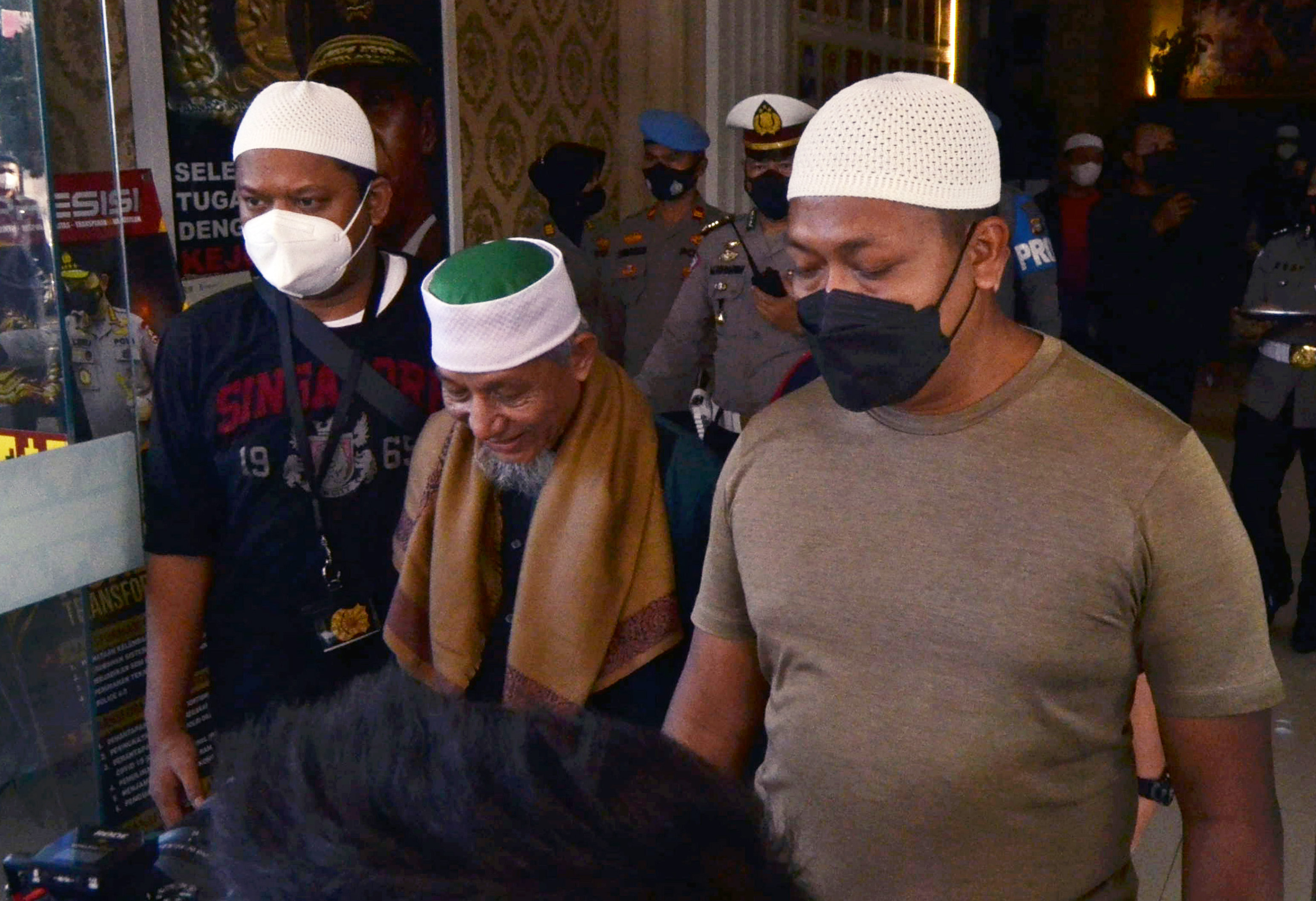 Pimpinan Khilafatul Muslimin Abdul Qadir Baraja (tengah) dikawal polisi berpakaian preman saat akan dibawa ke Polda Metro Jaya.