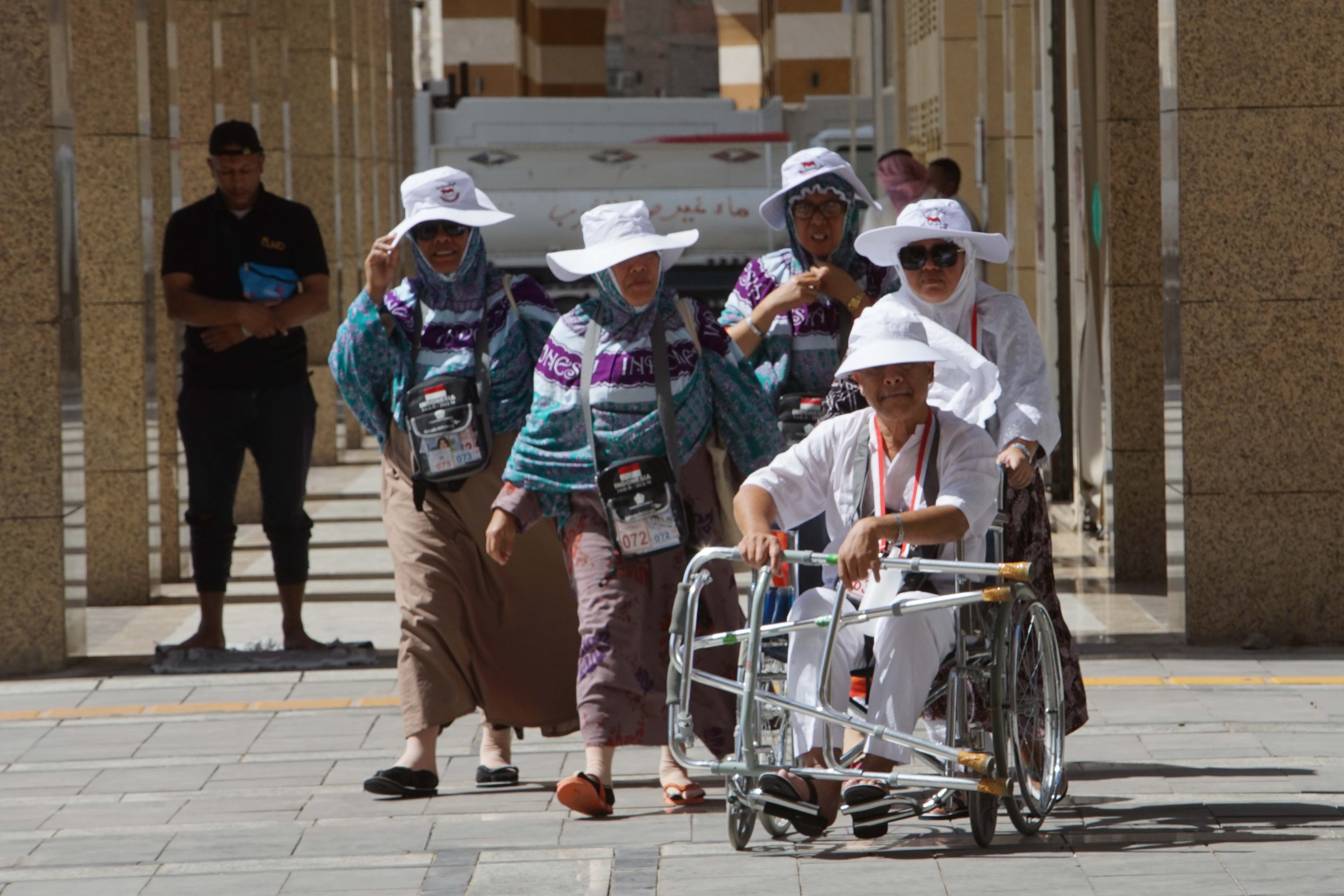 Jemaah haji Indonesia berlindung dari terik matahari usai beribadah di Madinah.