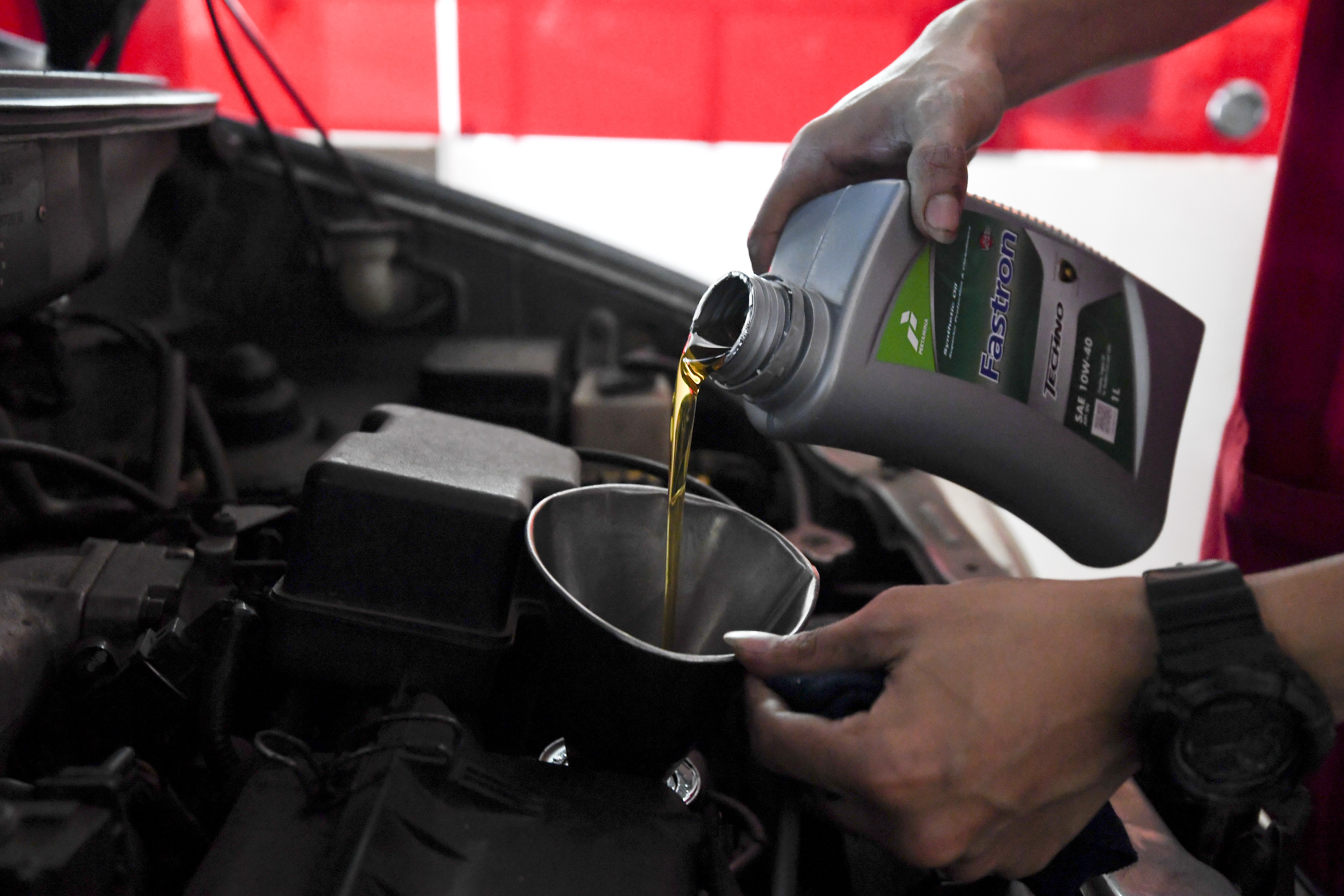 Montir menuangkan pelumas mesin ke sebuah kendaraan di gerai penjualan oli di Jakarta.