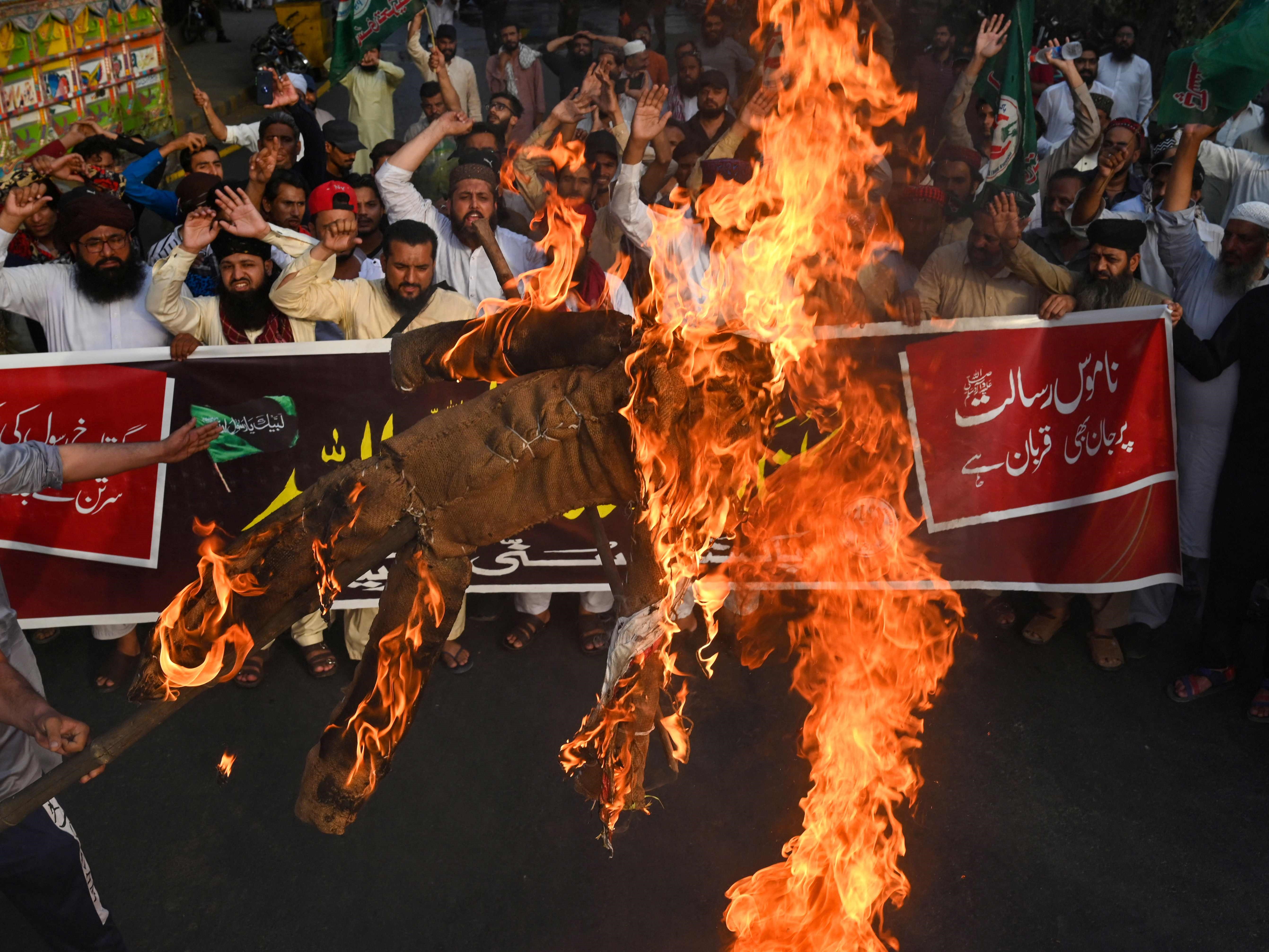 Umat Islam meneriakkan slogan-slogan di depan patung Perdana Menteri India Narendra Modi yang terbakar di Lahore, Minggu (12/6).