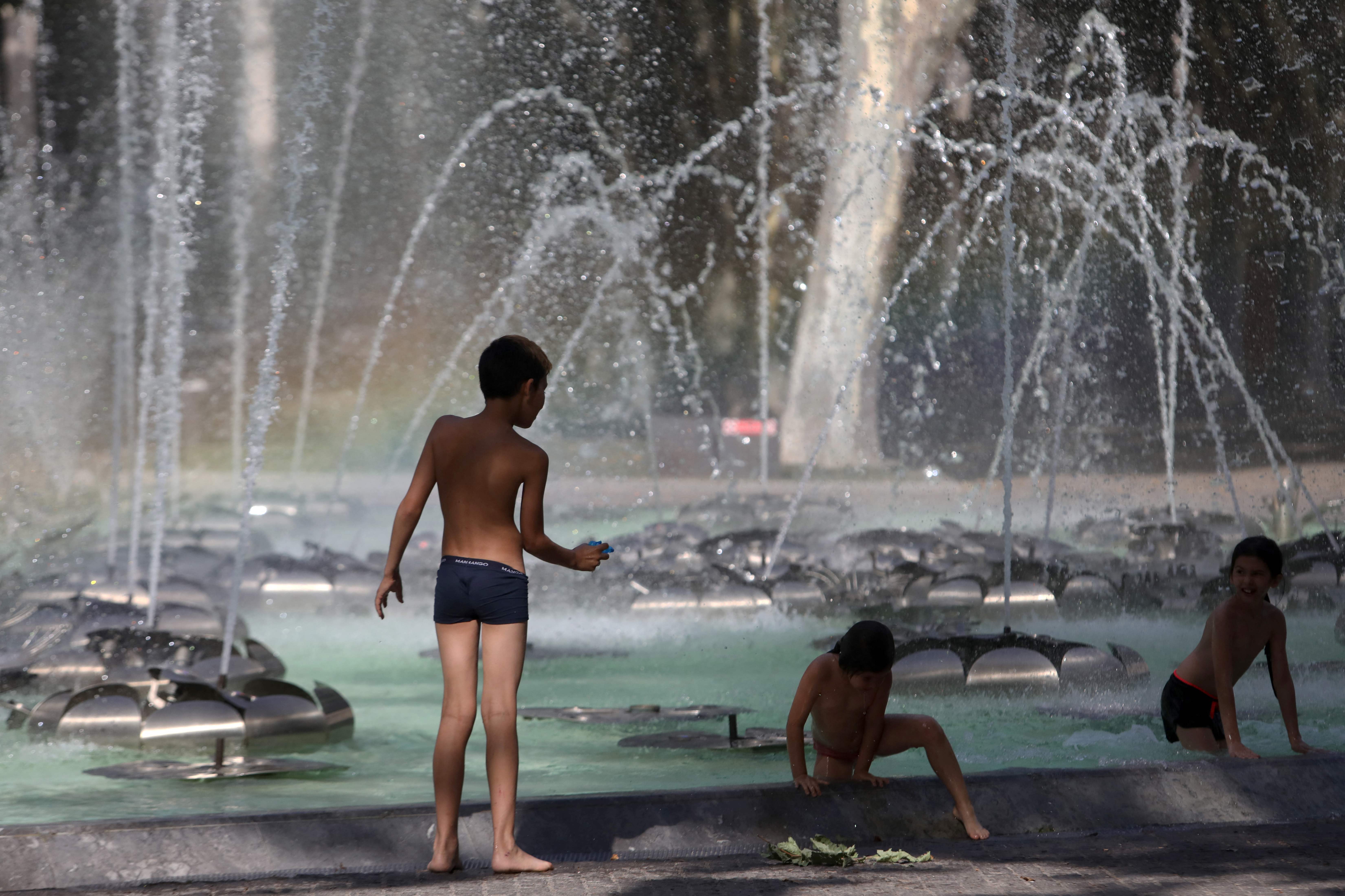 Anak-anak bermain di air mancur untuk menjaga kesejukan di kota Perpignan, Prancis selatan, Jumat (17/6) saat ini gelombang panas melanda er