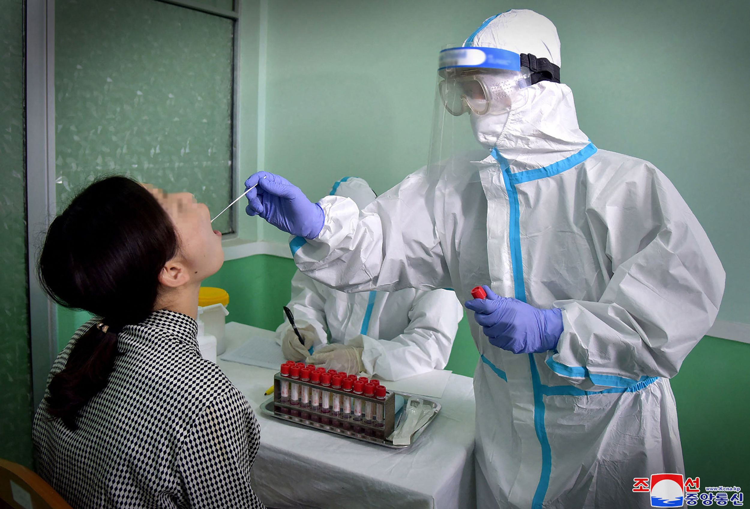 Petugas medis melakukan tes covid-19 terhadap warga Korea Utara.