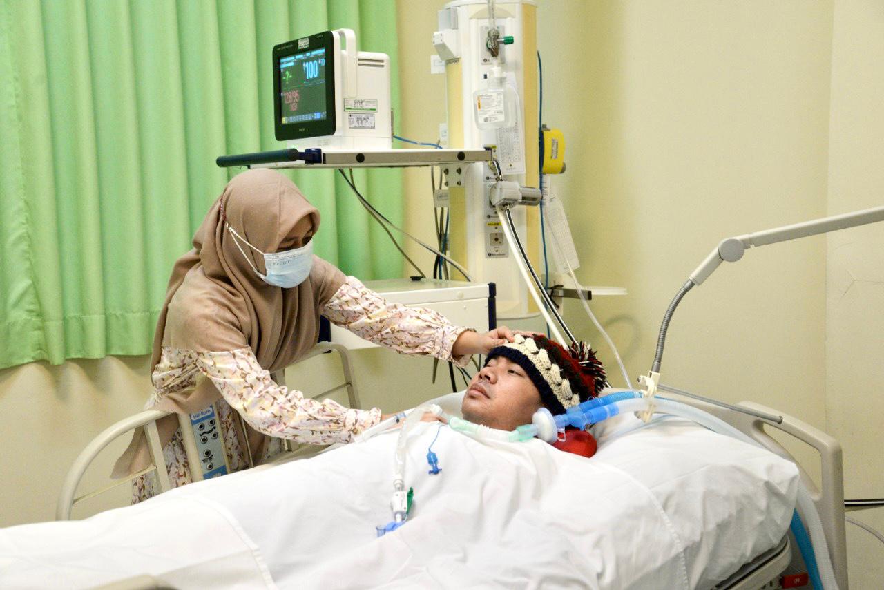 Sri Wulandari menemani Prantino di ICU rumah sakit, suaminya yang lumpuh total kecuali kepalanya akibat kecelakaan sejak 18 Desember 2016.