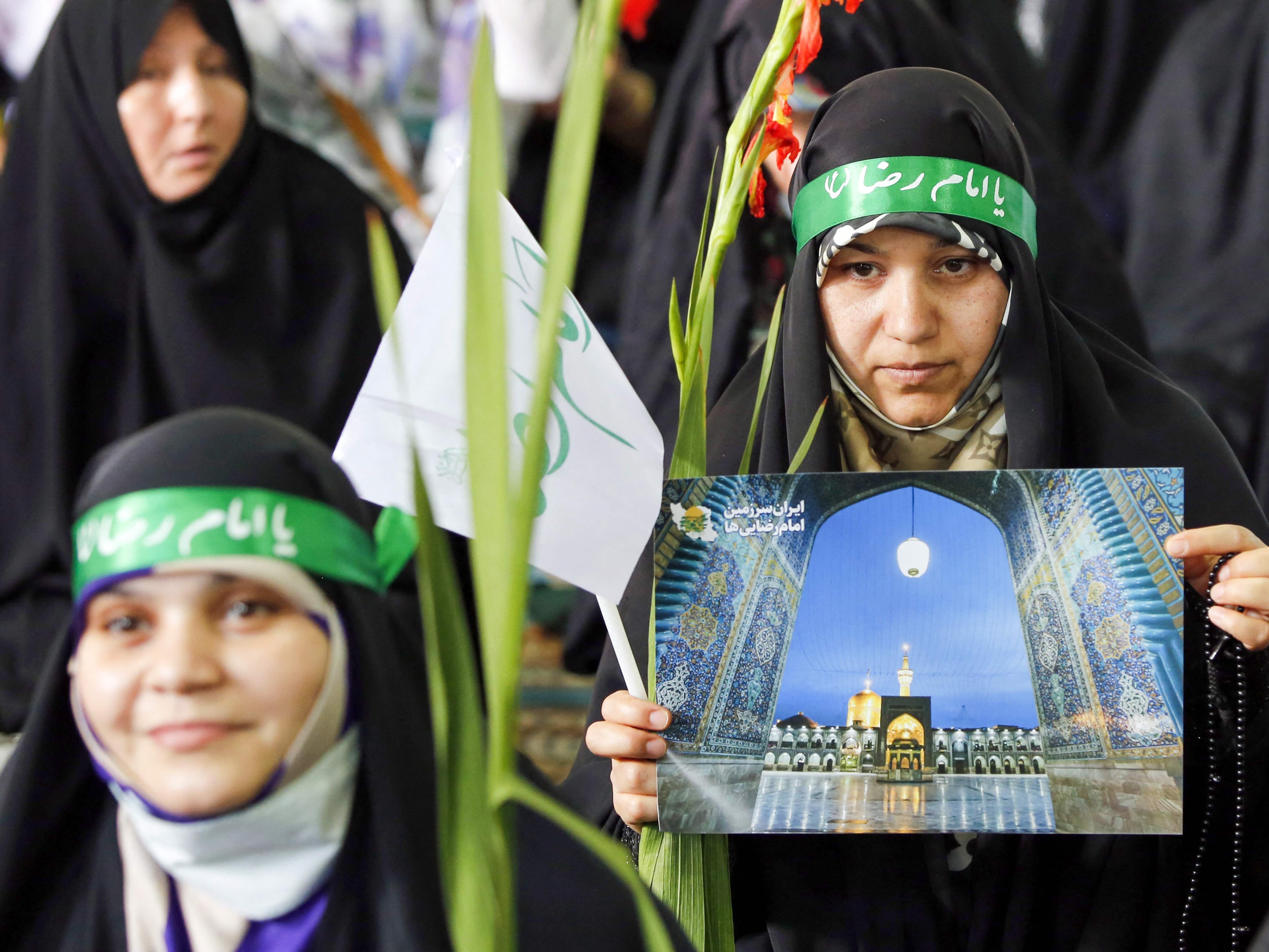 Orang-orang Iran melambaikan poster untuk merayakan ulang tahun Imam Reza, delapan Imam Syiah, selama pertemuan di Universitas Teheran.