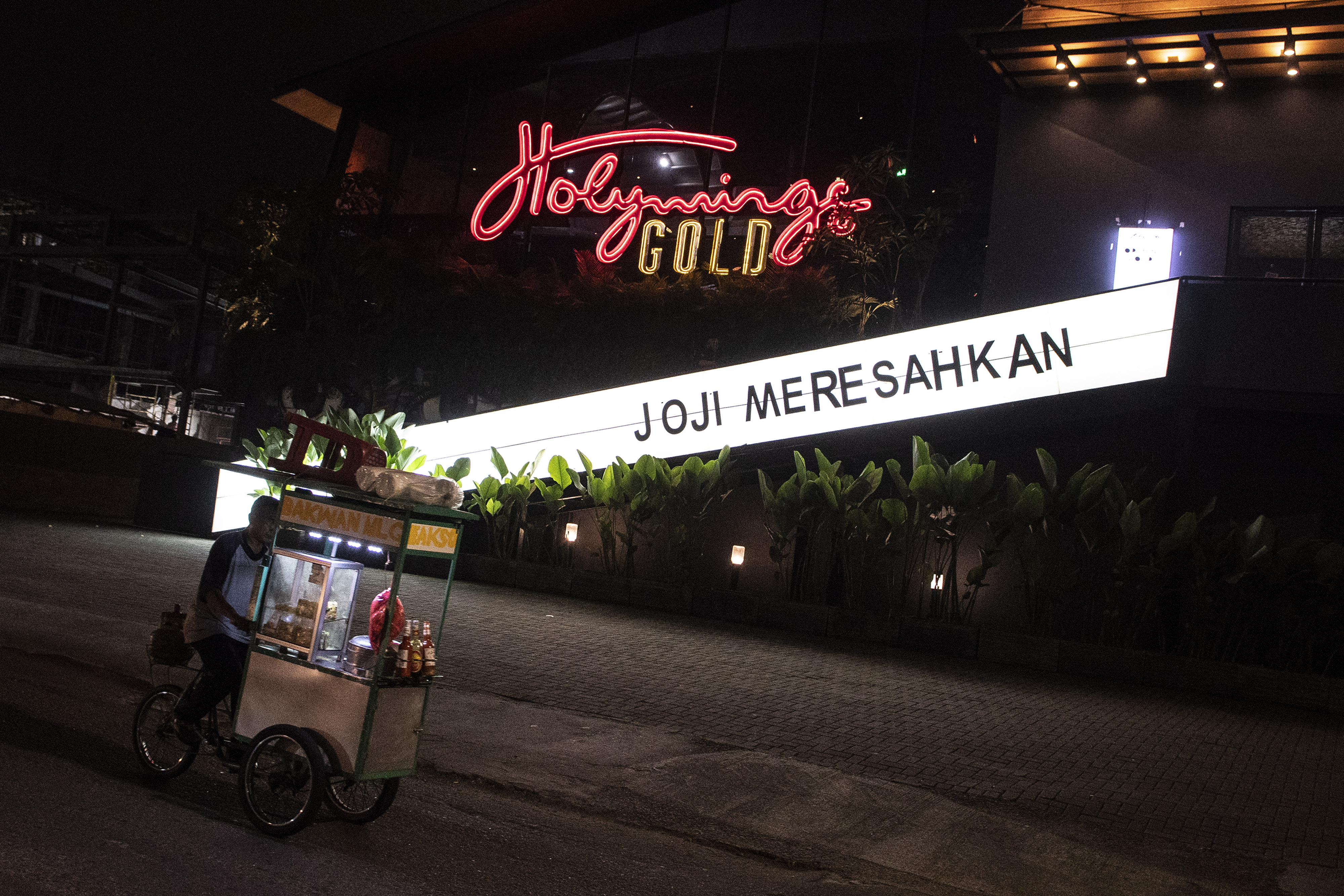 Pedagang melintasi outlet Holywing di Kelapa Gading, Jakarta, Senin (27/6).