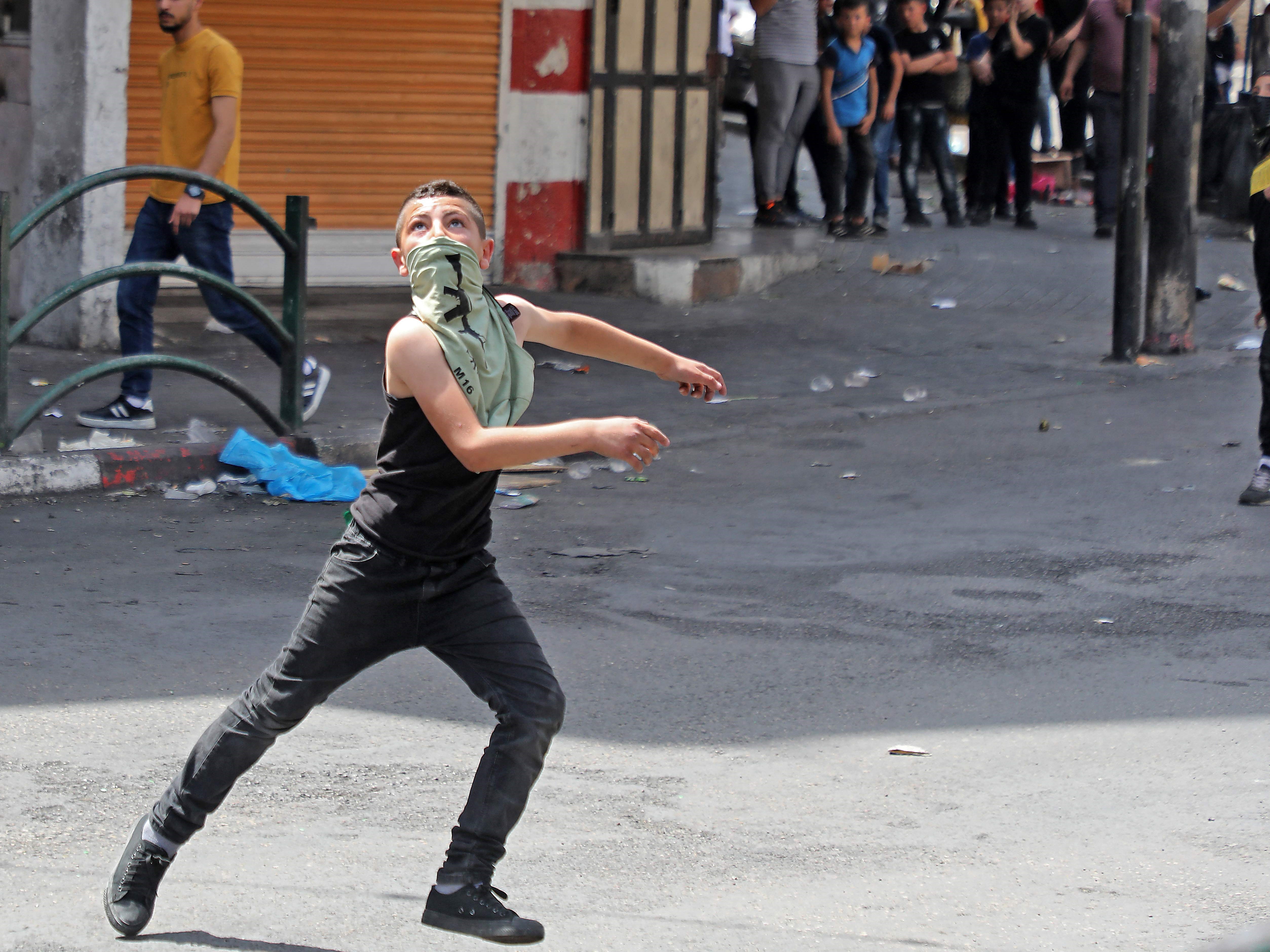 Seorang pelaku unjuk rasa Palestina bertopeng terlihat selama bentrokan dengan pasukan Israel.