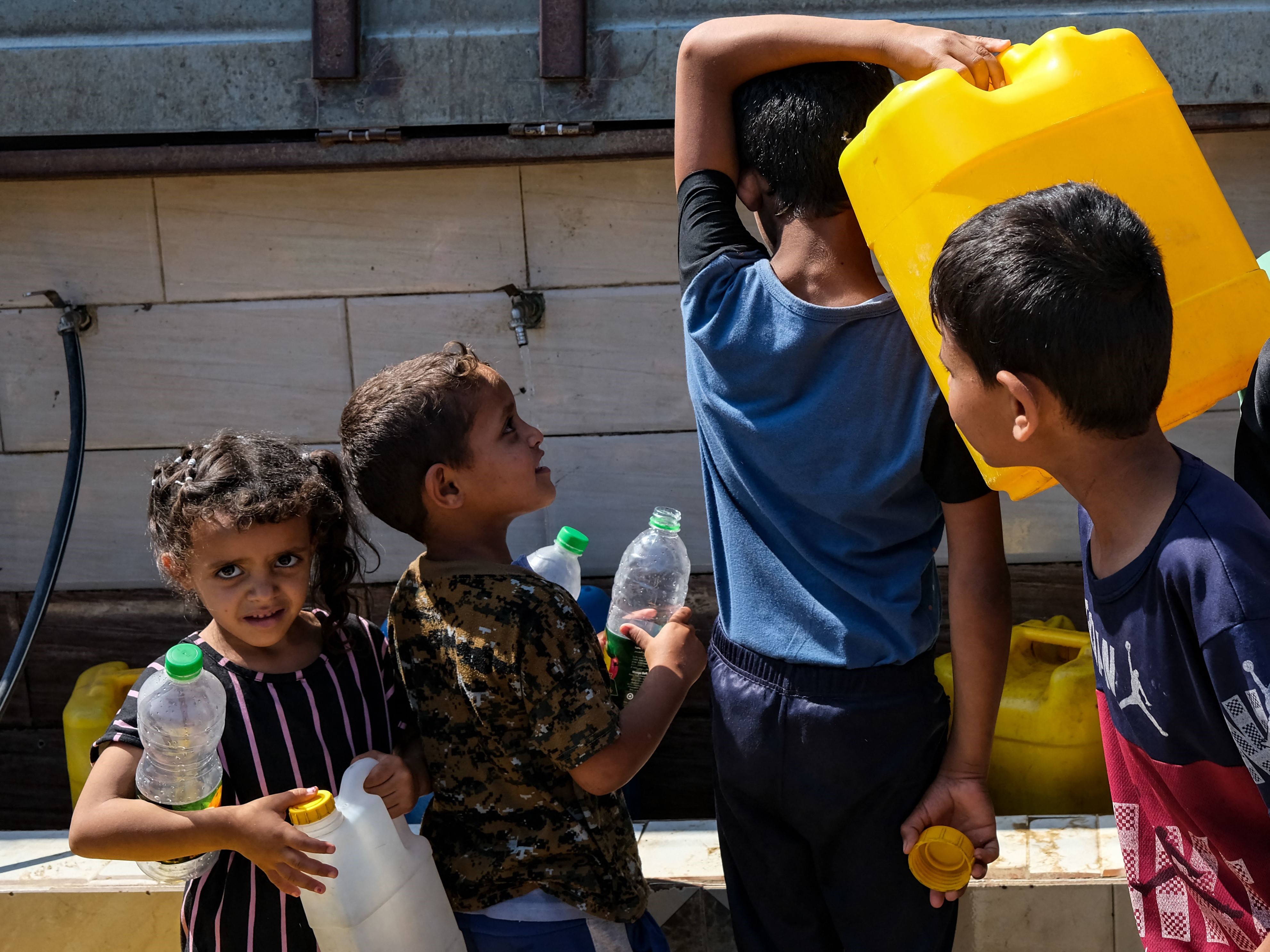 Anak-anak Palestina mengambil air dengan jeriken dari air mancur umum di lingkungan Al-Salam di kota Rafah di Jalur Gaza selatan.