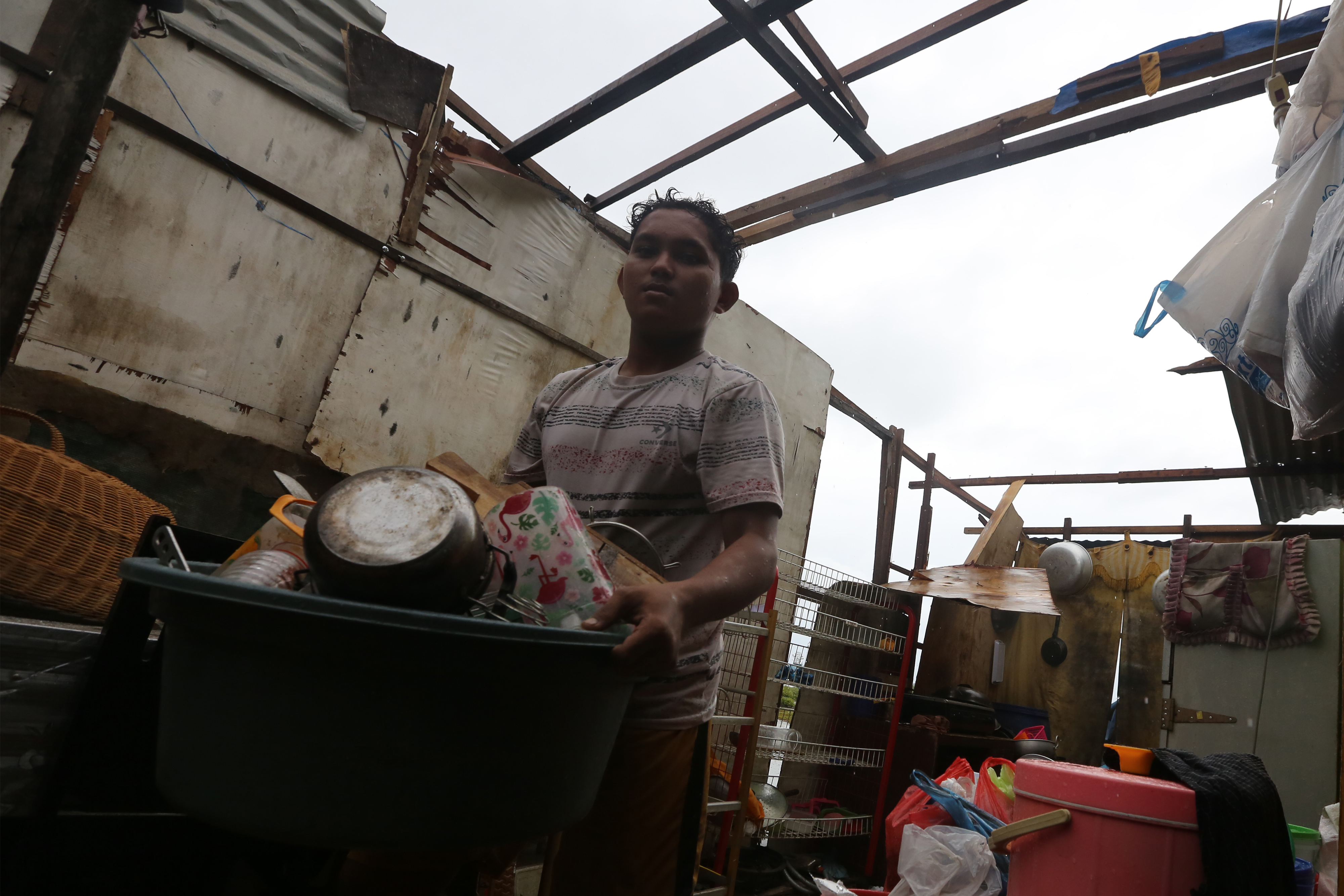  ANGIN KENCANG: Seorang warga membawa barang rumah tangga untuk diungsikan setelah atap rumahnya diterjang angin kencang di Banda Aceh.
