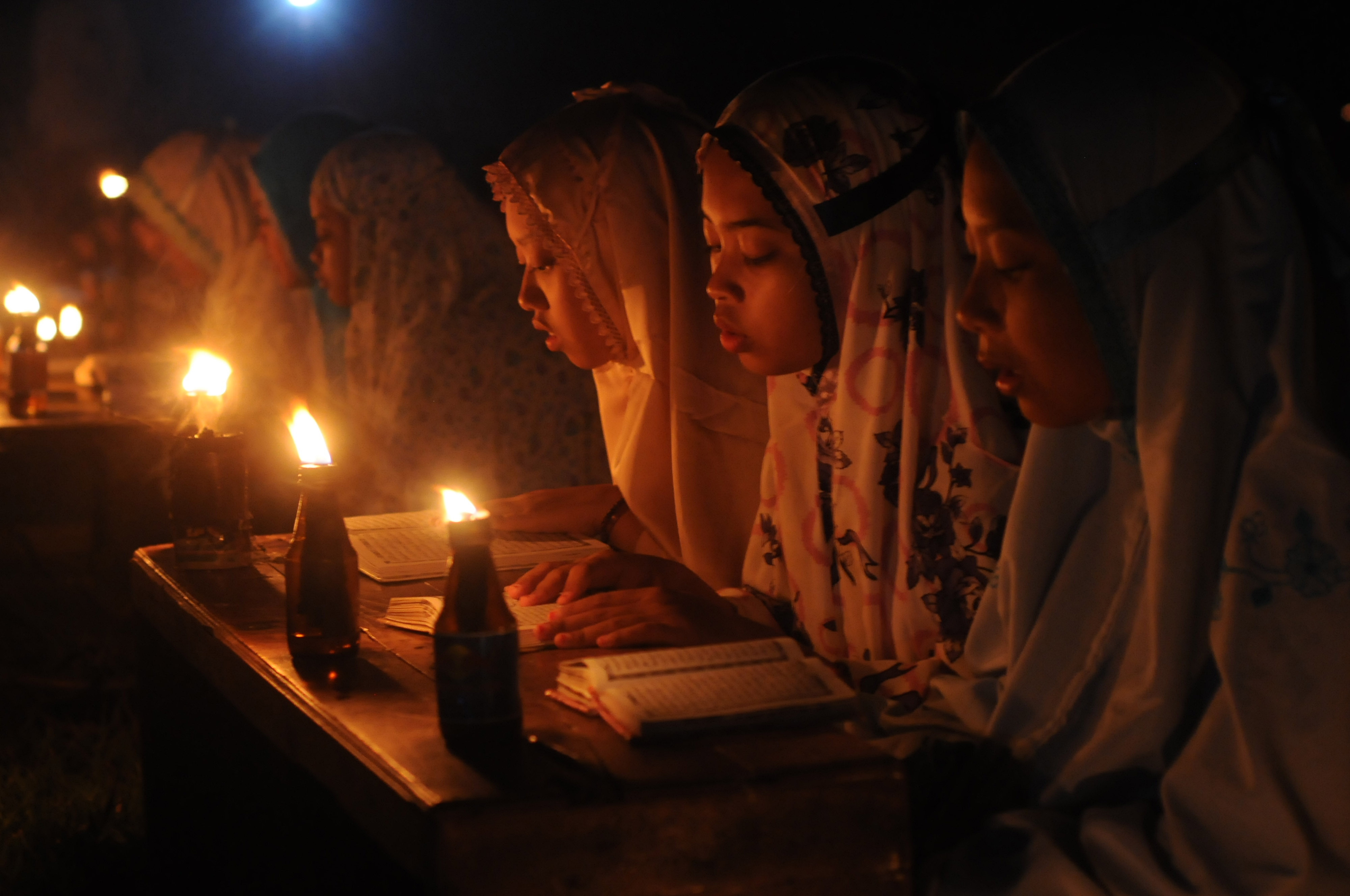 Ilustrasi santriwati tengah mengaji dengan disinari api dalam botol.