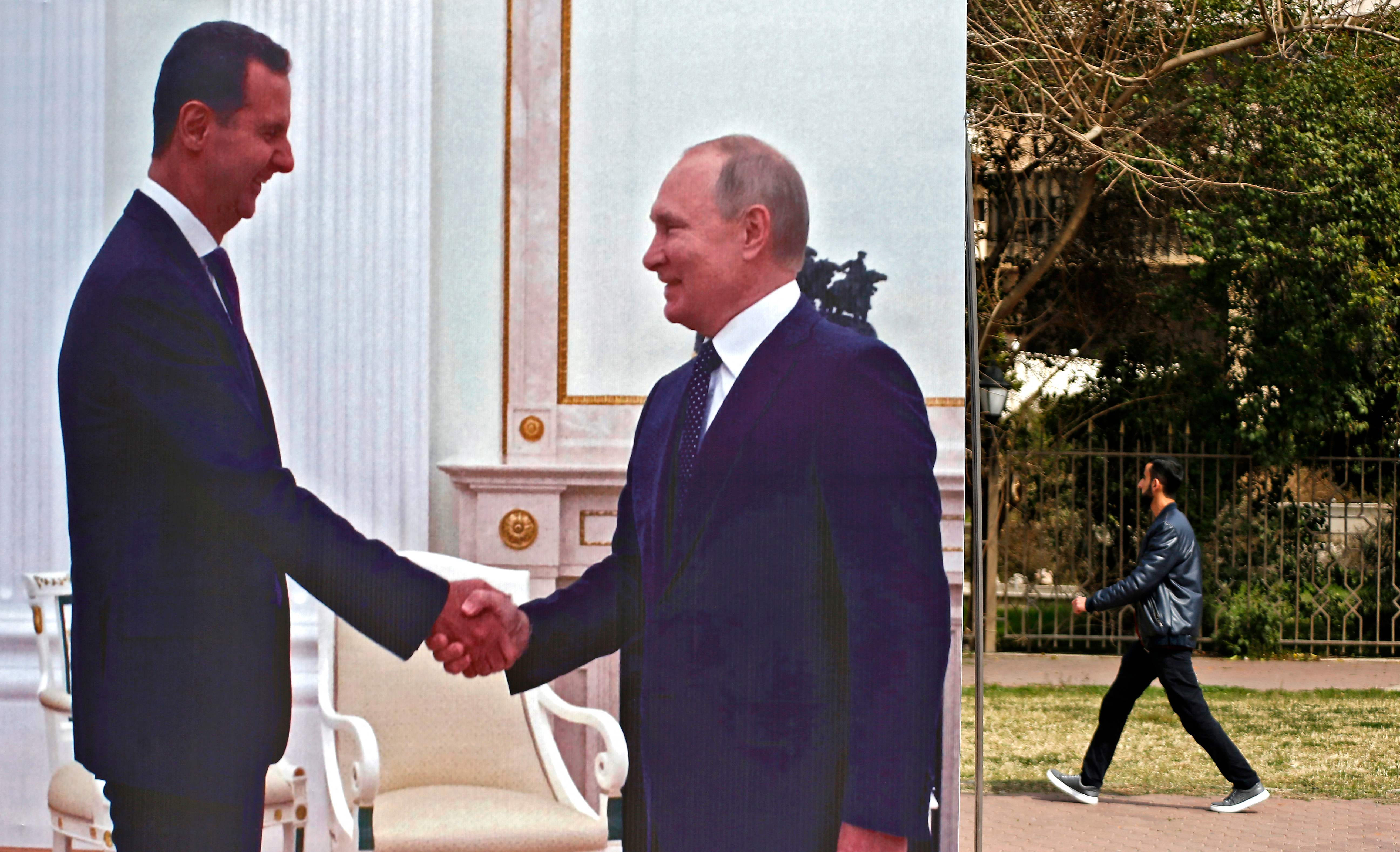 Poster besar yang menampilkan Presiden Suriah Bashar al-Assad berjabat tangan dengan Presiden Rusia Vladimir Putin terlihat di Damaskus.