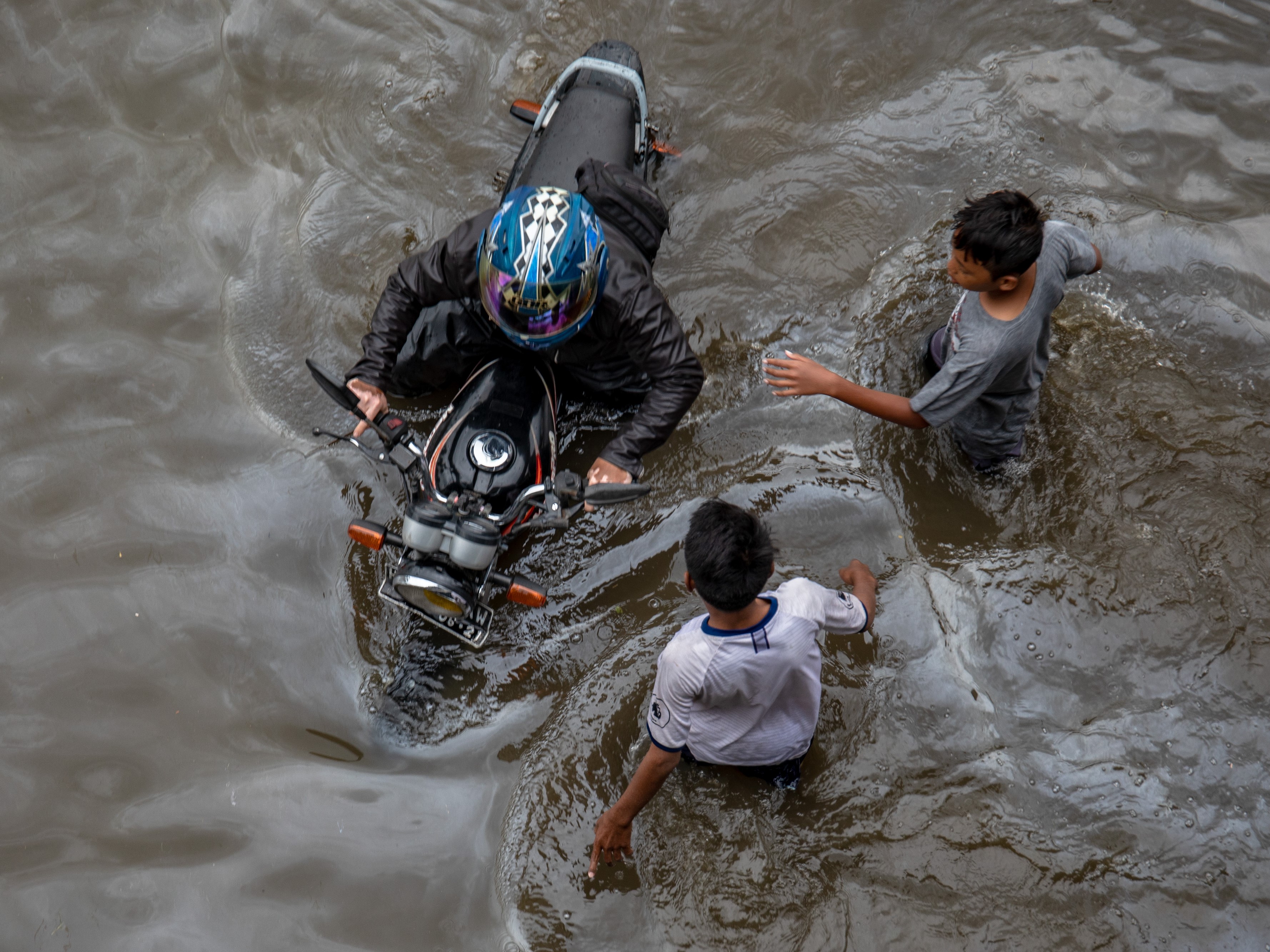 Seorang warga mendorong sepeda motornya yang mogok karena menembus banjir di Jalur Pantura Kaligawe-Genuk, Semarang, Jawa Tengah.
