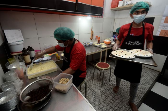 Dua pekerja membuat kue Klappertaart di Manado, Sulawesi Utara.  