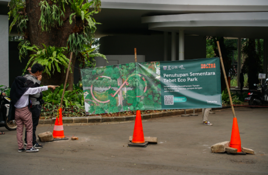 Warga melintas di depan spanduk informasi penutupan sementara Tebet Eco Park di Jakarta, Rabu (15/6/2022). 