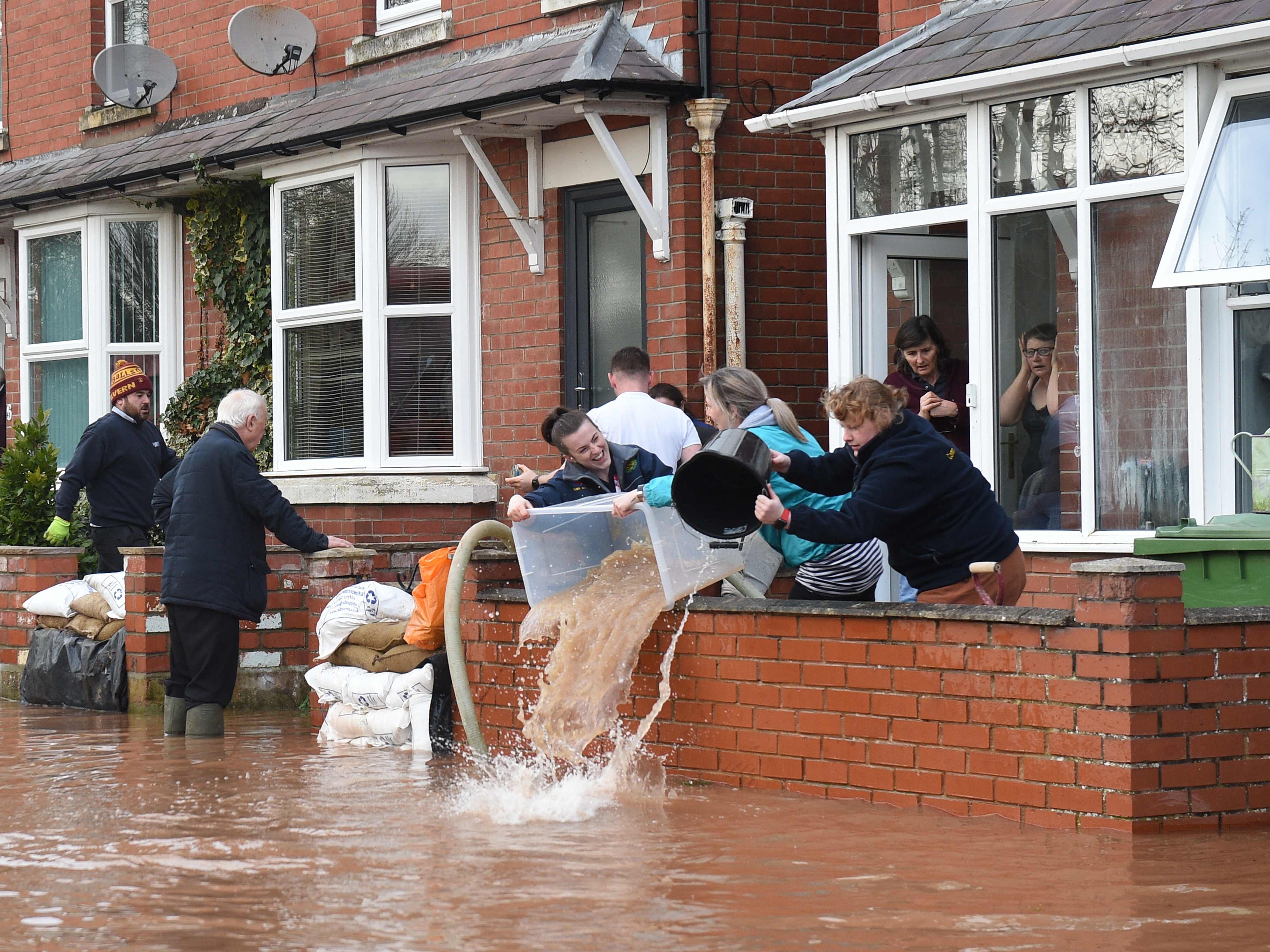 Orang-orang membuang air dari rumah yang kebanjiran setelah Sungai Wye meluap di Ross-on-Wye, Inggris barat, pada 17 Februari 2020.