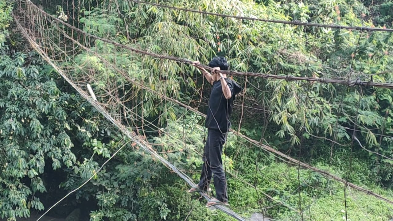 Warga Kampung Ciputat Desa Salamnunggal Kecamatan Cibeber Kabupaten Cianjur, Jawa Barat, nekat melintasi jembatan rusak yang hanya tinggal m